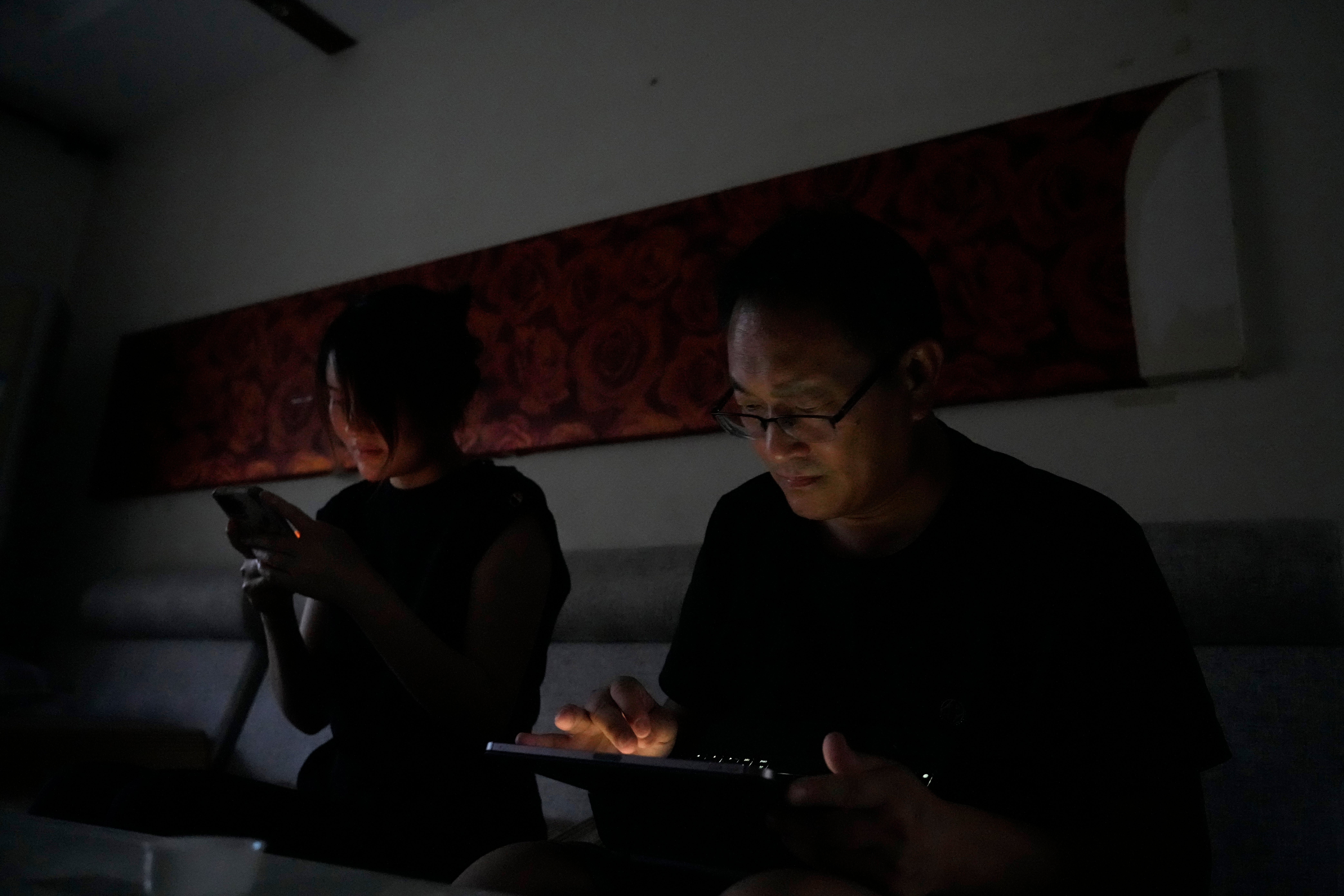 Wang Quanzhang and his wife Li Wenzu look at their phone and laptop in the dark after power was cut off for their apartment in Beijing's Changping district