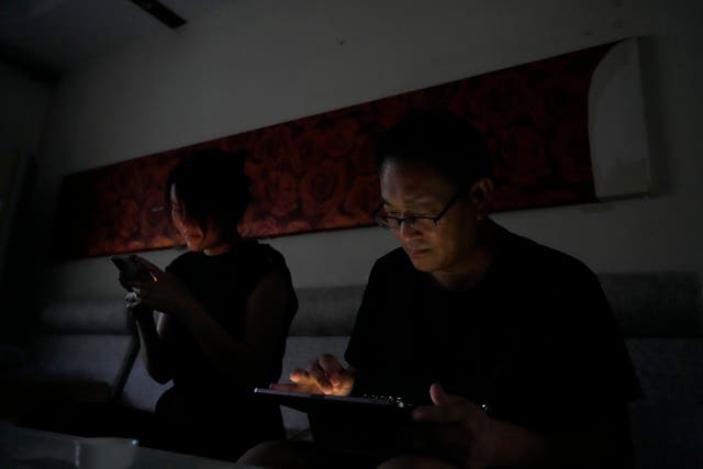 <p>Wang Quanzhang and his wife Li Wenzu look at their phone and laptop in the dark after power was cut off for their apartment in Beijing's Changping district</p>