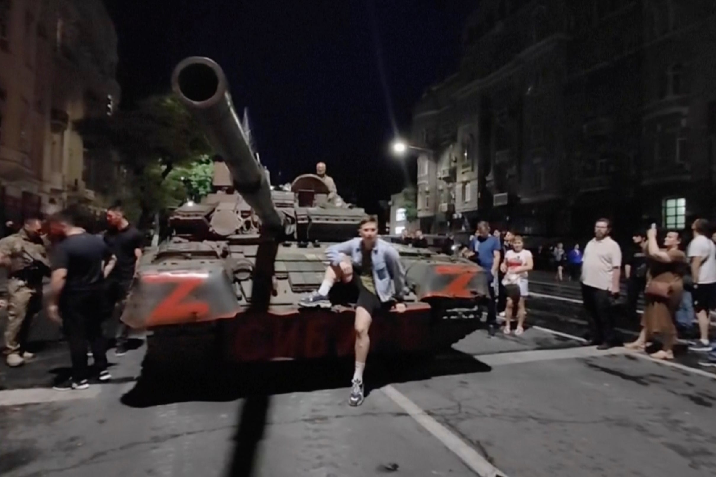 Residents of the southern Russian city of Rostov take photos of an armored vehicle in the street as they talk with military personnel