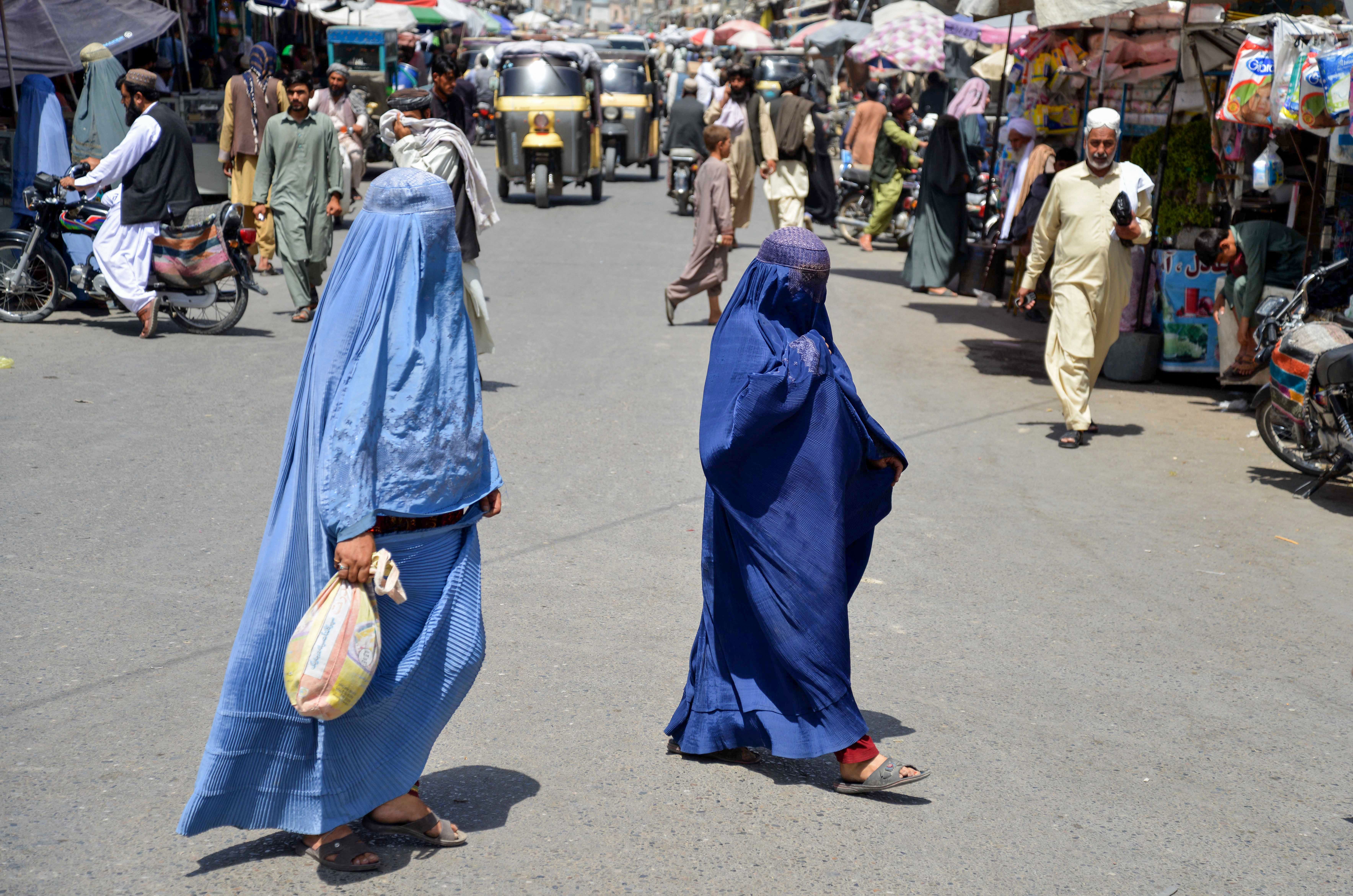 Afghan women walk along a road at a market area in Kandahar