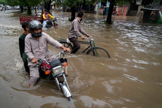 <p>Motorcyclists drive through a flooded road caused by heavy rainfall, in Lahore, Pakistan on 26 June </p>