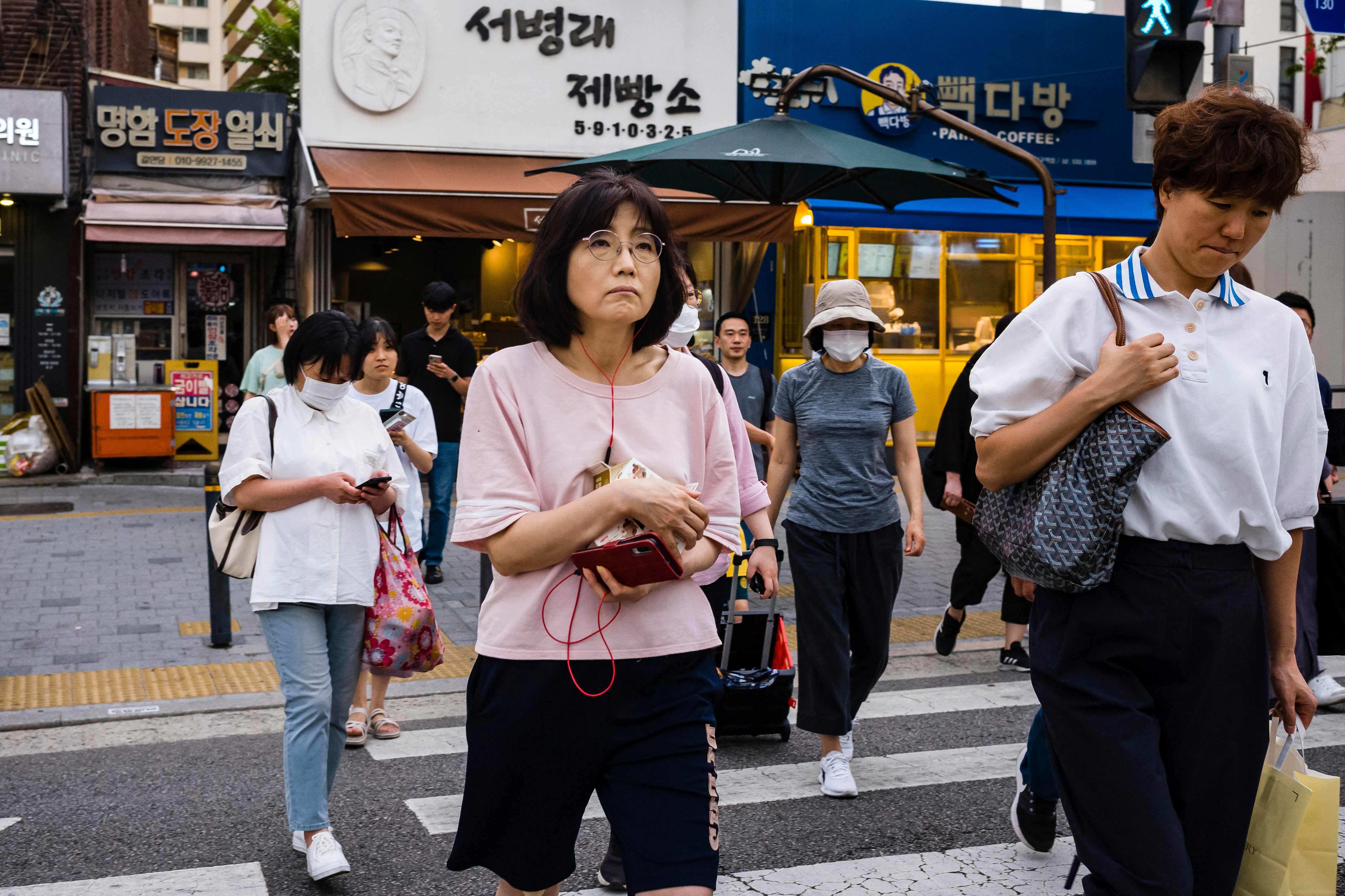 Pedestrians walk across a road in Seoul