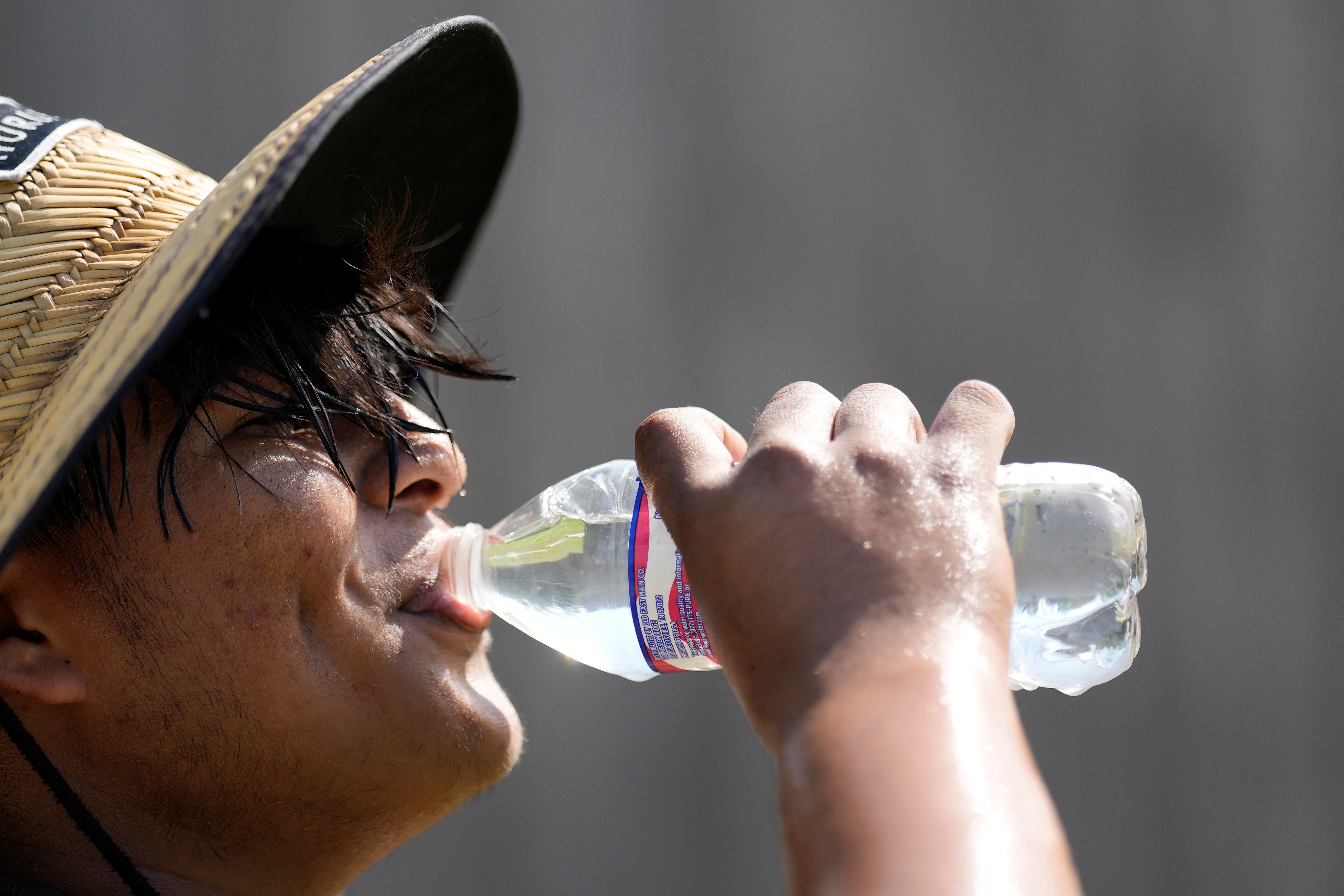 Carlos Rodriguez drinks water while taking a break from digging fence post holes in Houston in June