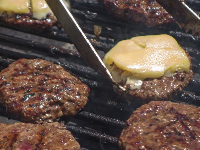 <p>Burgers on the grill at a farmers’ market </p>