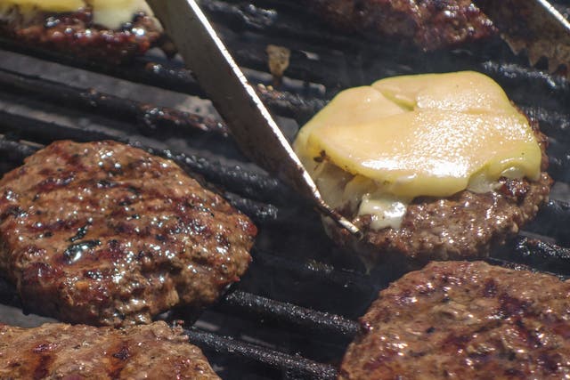 <p>Burgers on the grill at a farmers’ market </p>