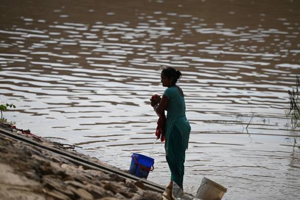 A woman does her laundry next to a flooded area near the banks of the Yamuna River