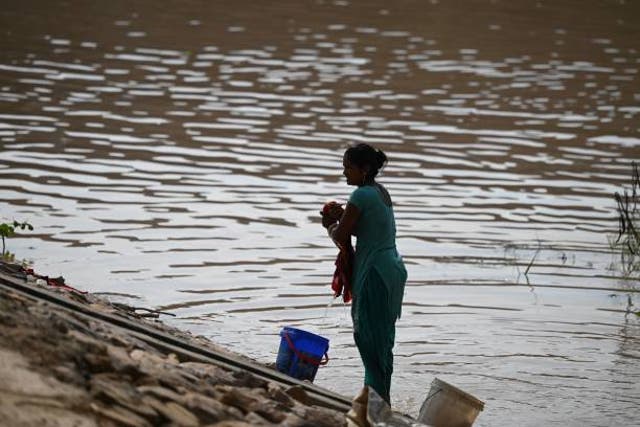 <p>A woman does her laundry next to a flooded area near the banks of the Yamuna River </p>