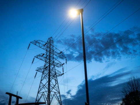 <p>File image: Night time falls behind electricity pylons and a sub station in Manchester. The UK government is going to continue investing in unbataed gas power plants beyond 2030 </p>