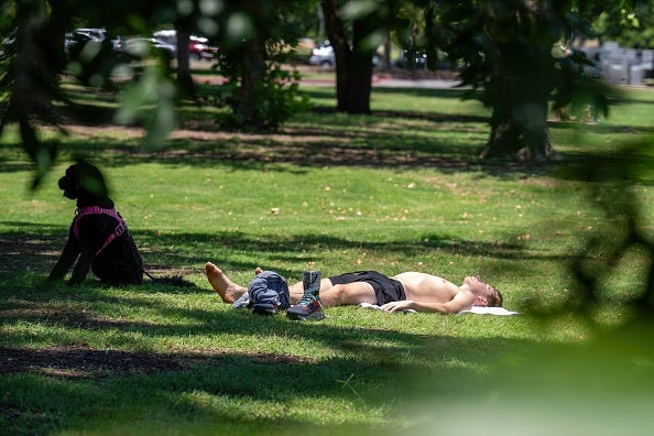 A resident and his dog sunbath at Zilker Park on June 27, 2023 in Austin, Texas