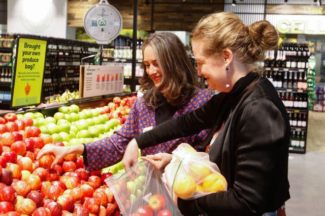 <p>Catherine Langabeer, left, the head of sustainability at the Countdown chain of supermarkets, and Associate Environment Minister Rachel Brooking demonstrate collecting fruit in reusable polyester mesh bags on Thursday</p>