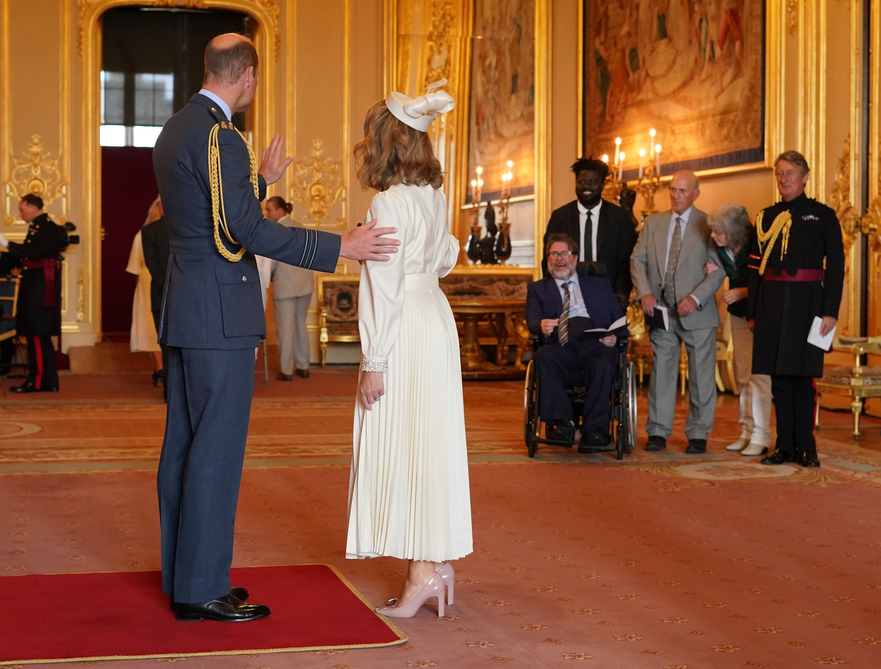 Kate Garraway is watched by her husband Derek Draper as she is made a Member of the Order of the British Empire by the Prince of Wales at Windsor Castle