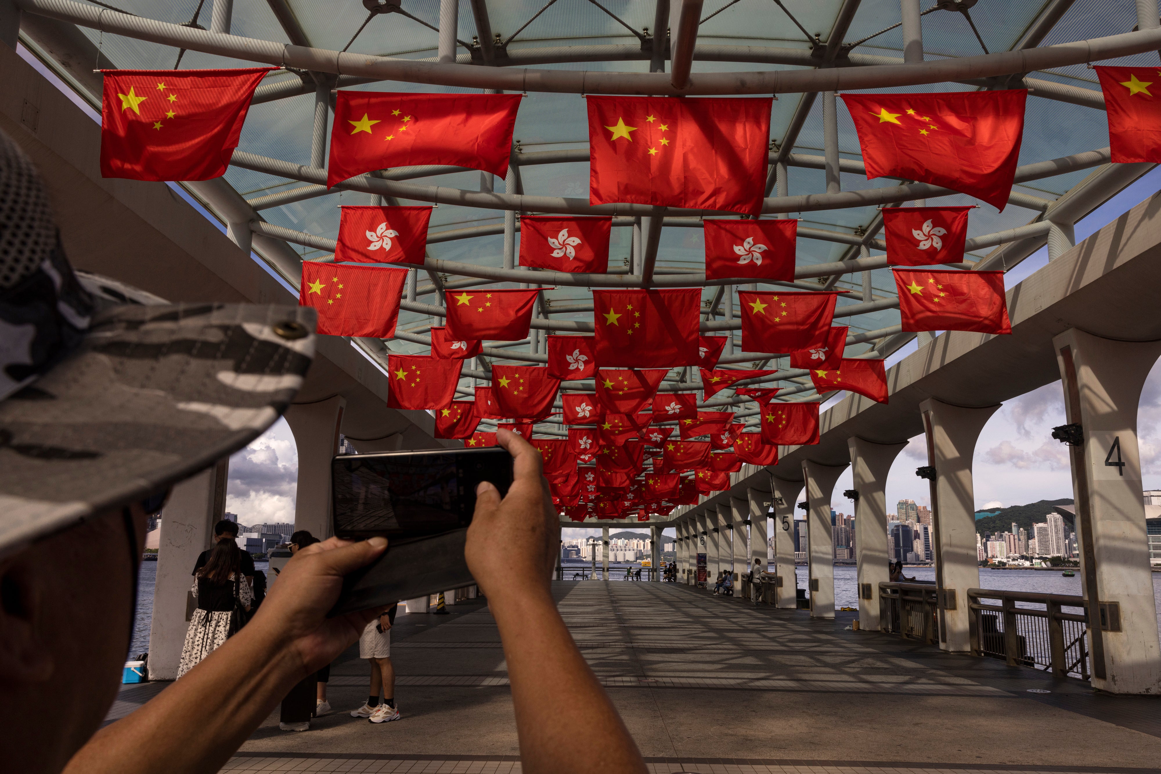 File. Mainland Chinese tourists take photographs as Chinese and Hong Kong flags are strung to mark the 26th anniversary of the city’s handover from Britain to China in Hong Kong, on June 27, 2023. A Japanese journalist was barred from entering Hong Kong without a clear reason and was sent back to his country, a Japanese newspaper reported Friday, 30 June 2023 raising concerns over the city’s shrinking press freedoms