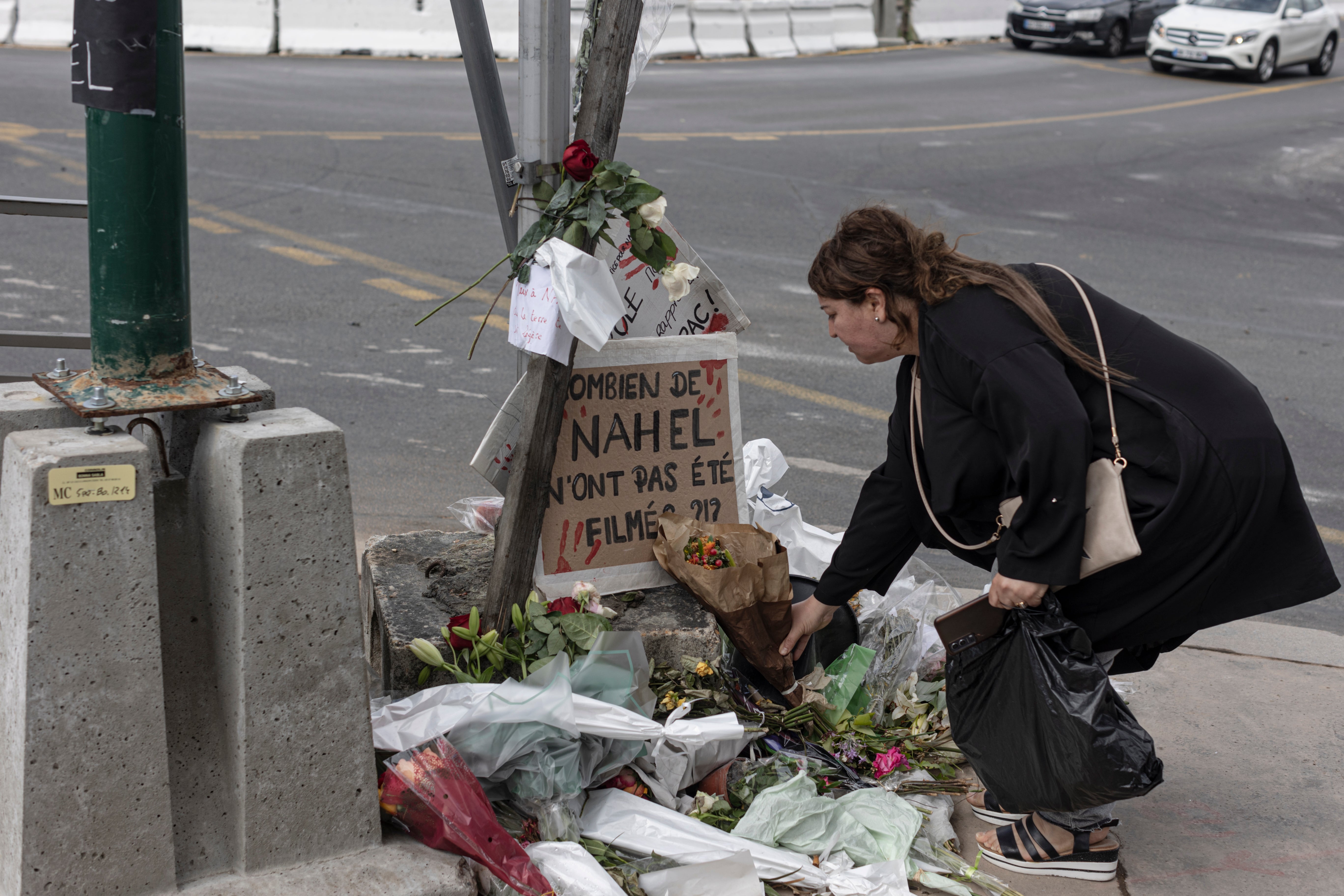 A woman pays her respects at the site where Nahel died