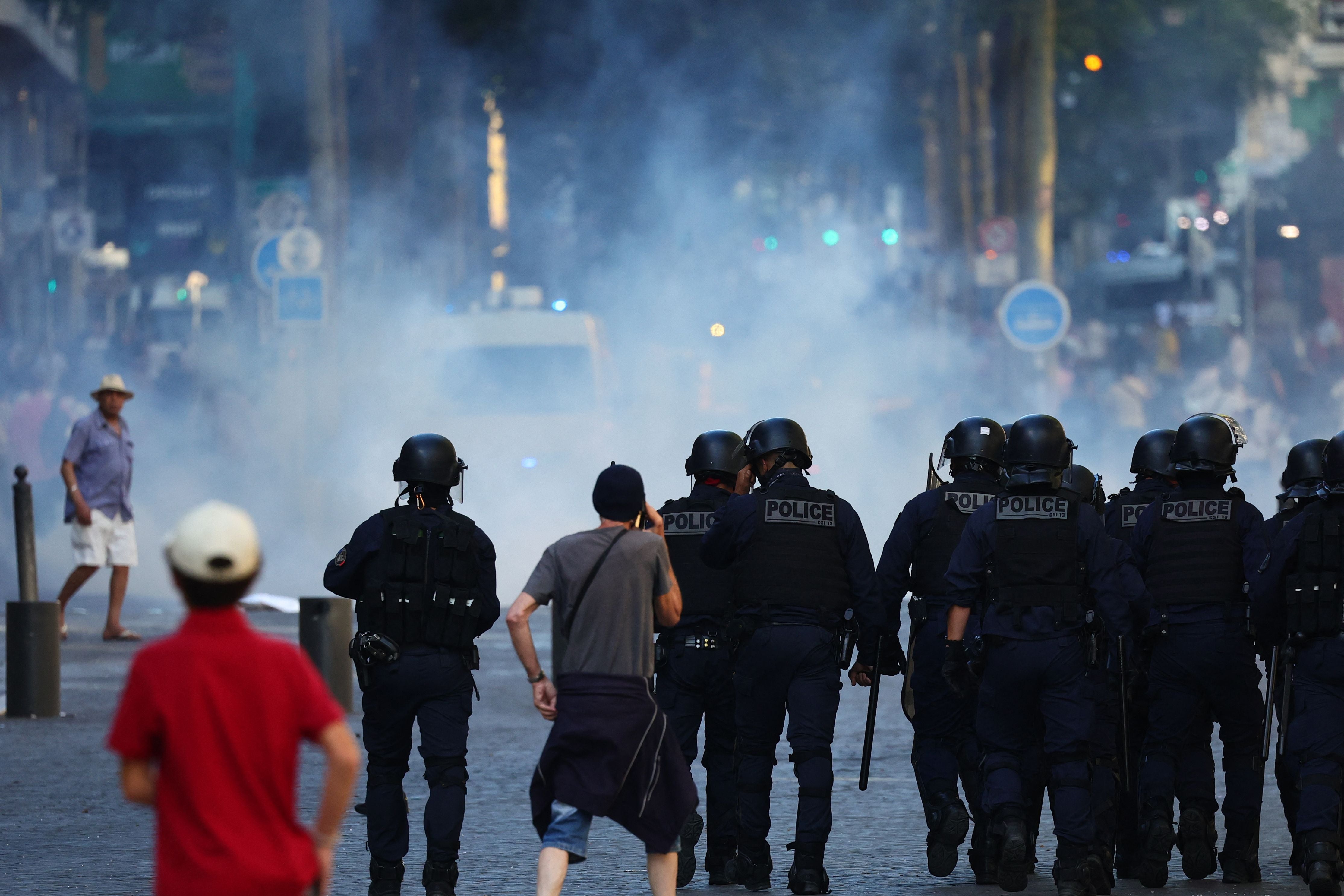 Police officers walk as they try to disperse protesters with tear gas during a demonstration against police in Marseille, southern France