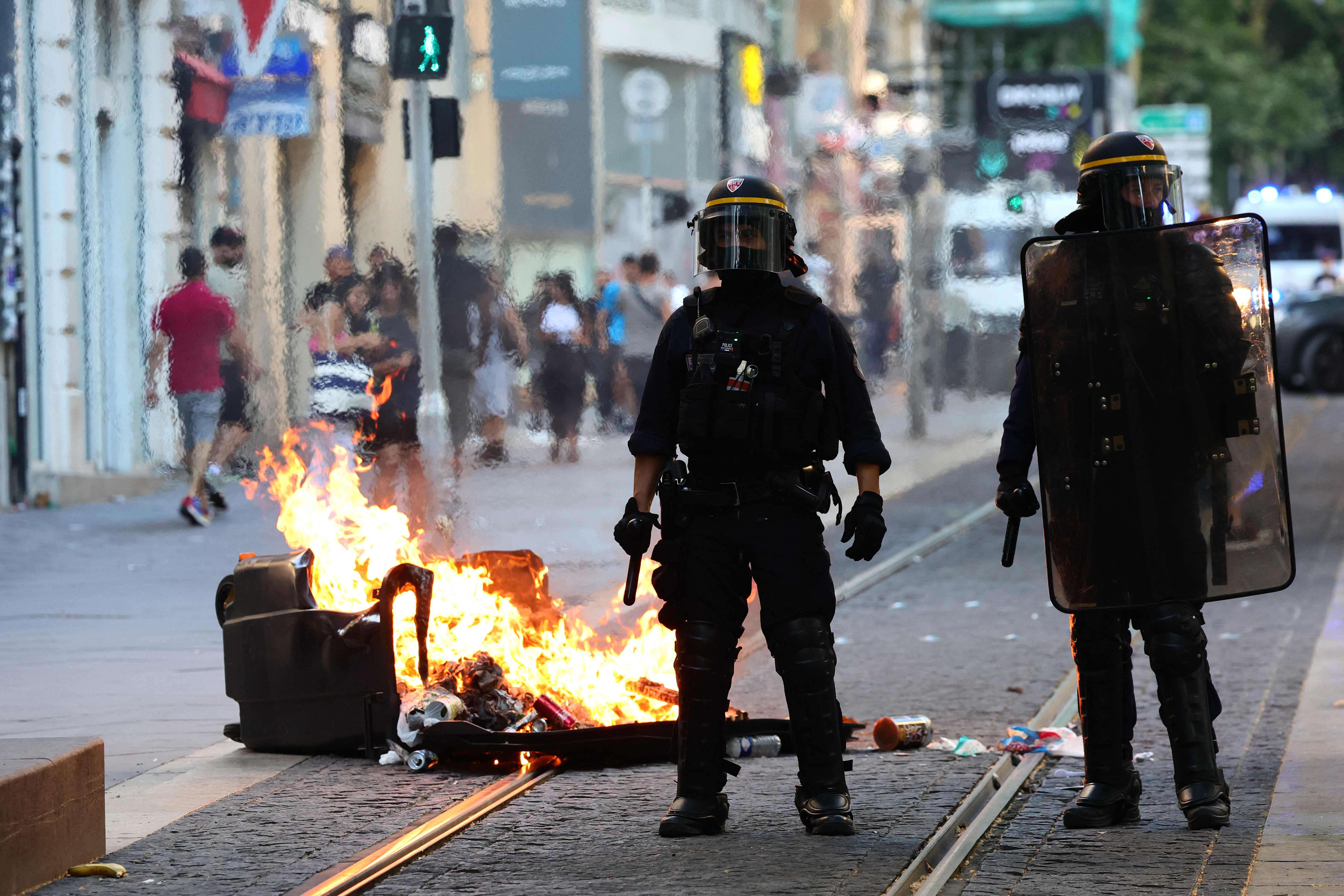 French riot police officers stand guard next to a burnt out trash bin during a demonstration against police in Marseille on Saturday