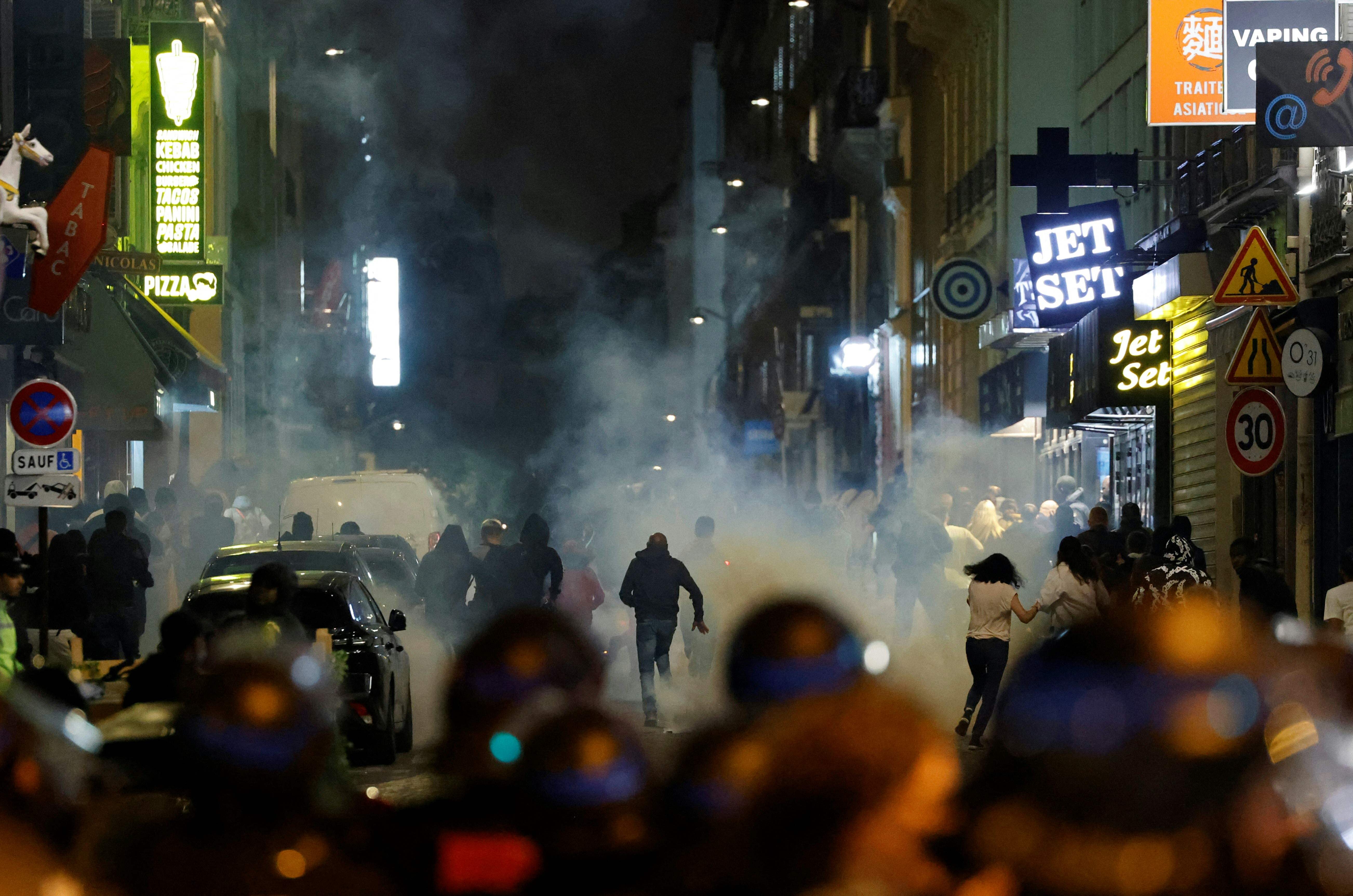 Demonstrators run as French police officers use tear gas in Paris on Sunday