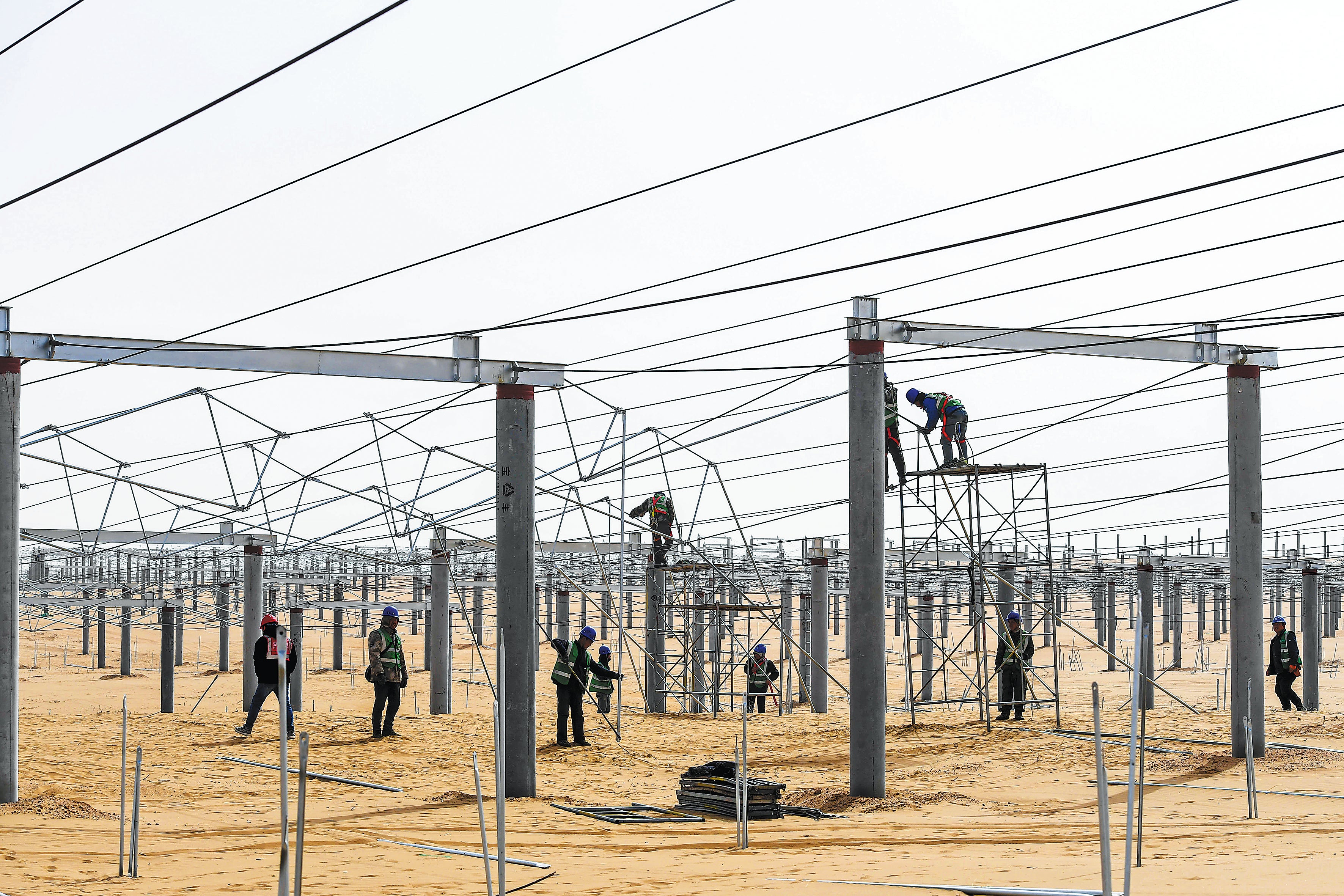 Workers set up frameworks for a solar power project in Kubuqi desert in the Inner Mongolia autonomous region