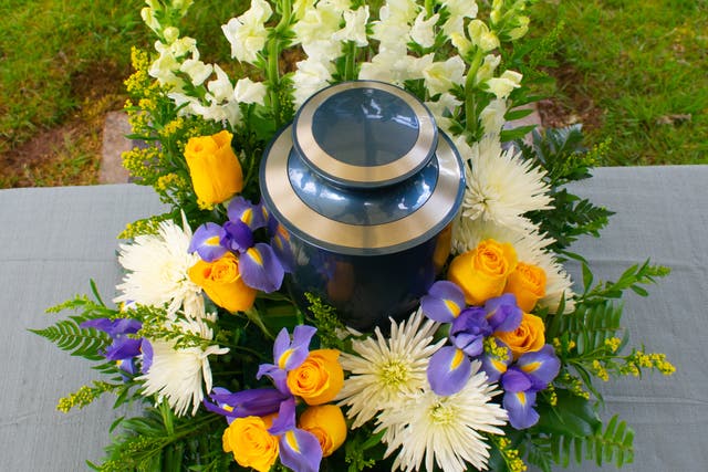 <p>A cremation urn  with floral arrangement at a funeral ceremony</p>