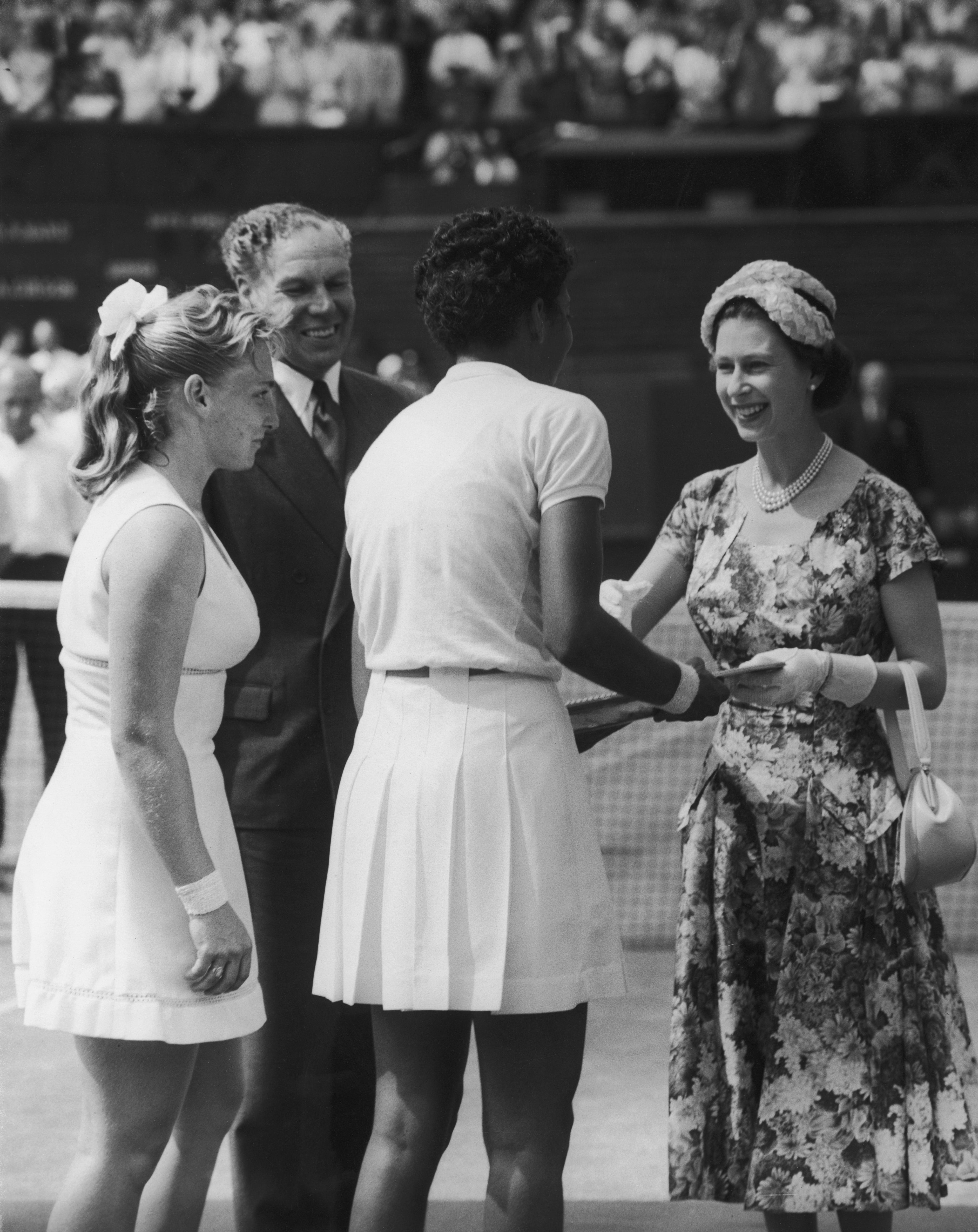 Queen Elizabeth II presents the trophy to American tennis player Althea Gibson (1927 - 2003) after she won the Women's Singles final at Wimbledon, 6th July 1957