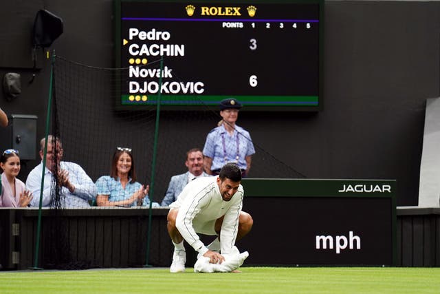 Novak Djokovic wipes the damp court with a towel (Zac Goodwin/PA)