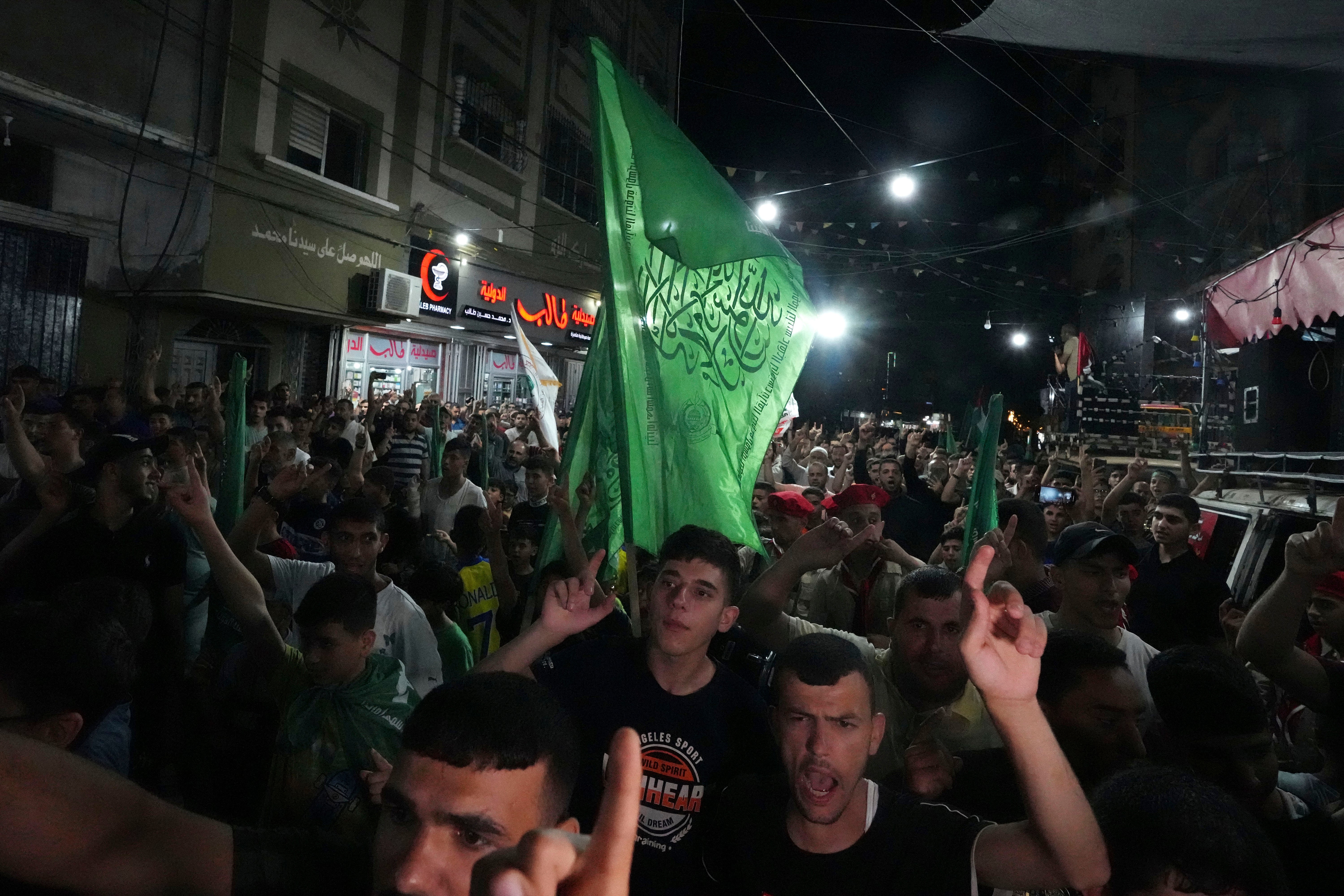 Hamas supporters wave green Islamic flags while raise their hands up and chant slogans