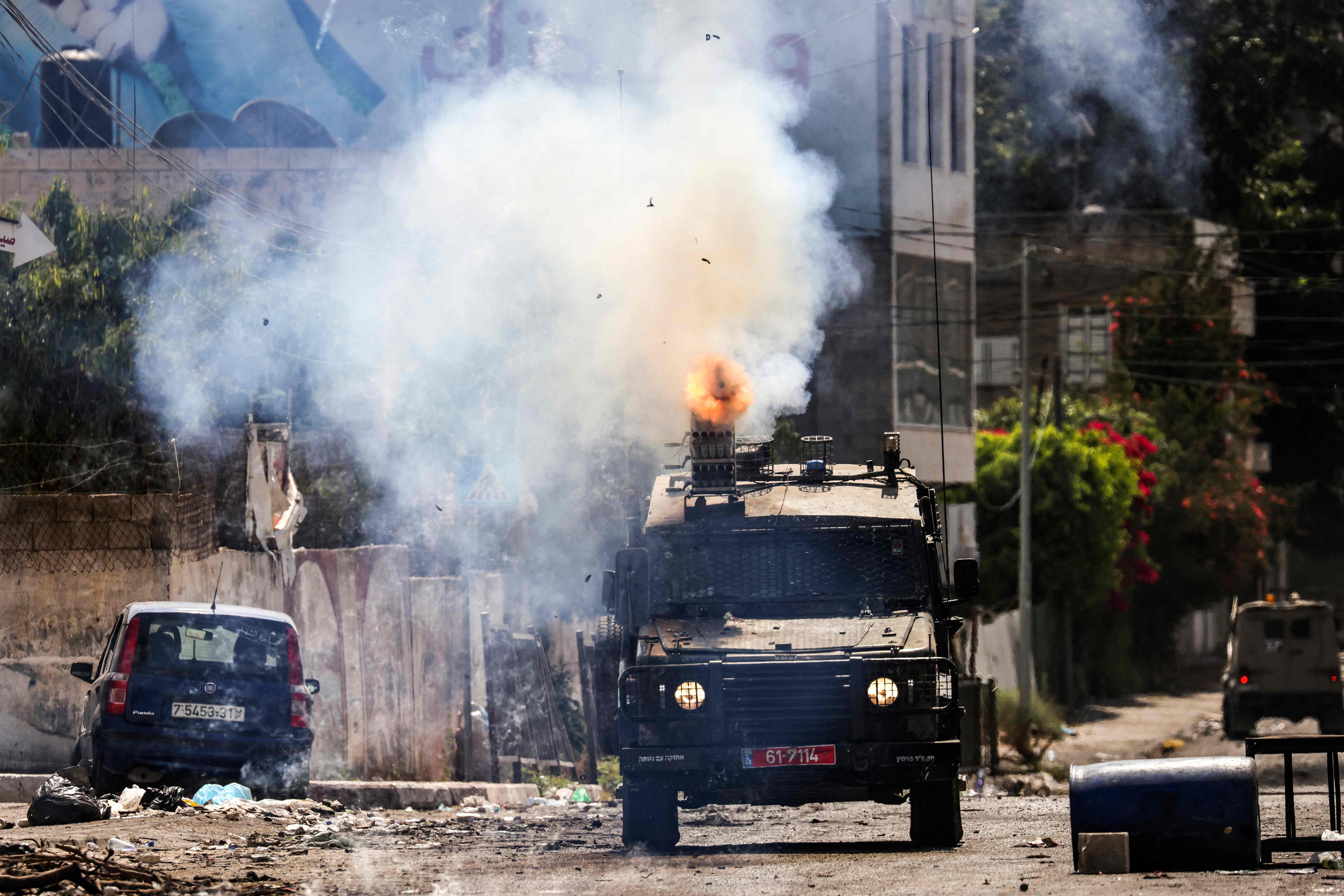 An Israeli armoured vehicle fires tear gas during an ongoing military operation in Jenin city