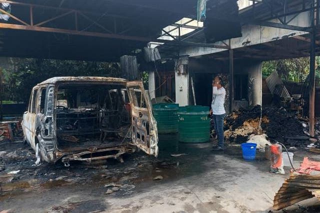 <p>A man stands next to a burnt vehicle at the ransacked residence of Minister of State for External Affairs Rajkumar Ranjan Singh in Imphal on 16 June 2023</p>