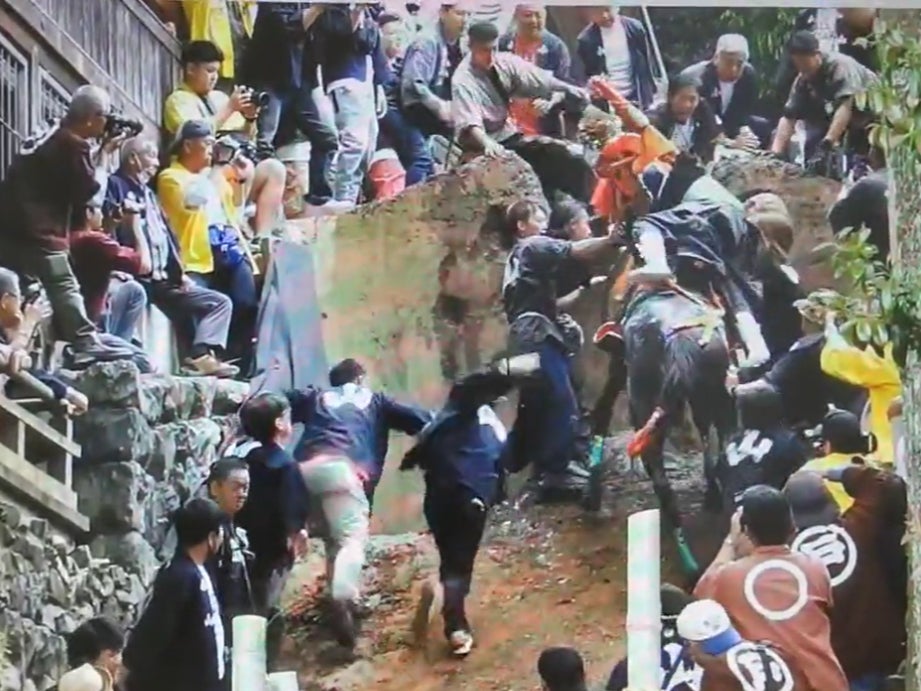 A horse falls back while climbing up a steep wall during the race