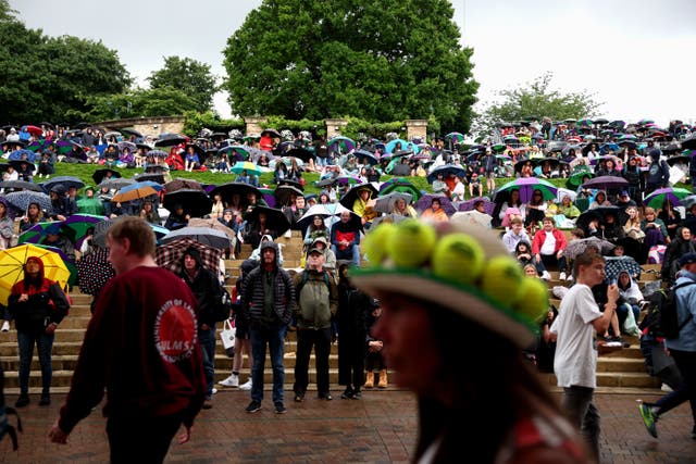 <p>Spectators shelter from the rain with umbrellas and watch the Centre Court and Court 1 matches on the hill during day two of The Championships Wimbledon 2023 at All England Lawn Tennis and Croquet Club</p>