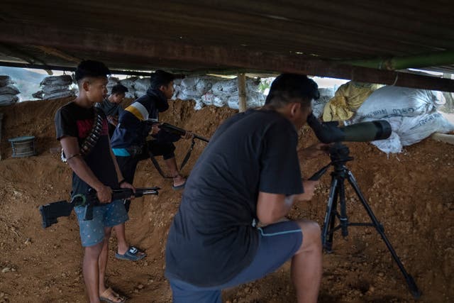 <p>Armed Meitei community members keep a watch from a bunker on rival tribal Kuki community bunkers </p>