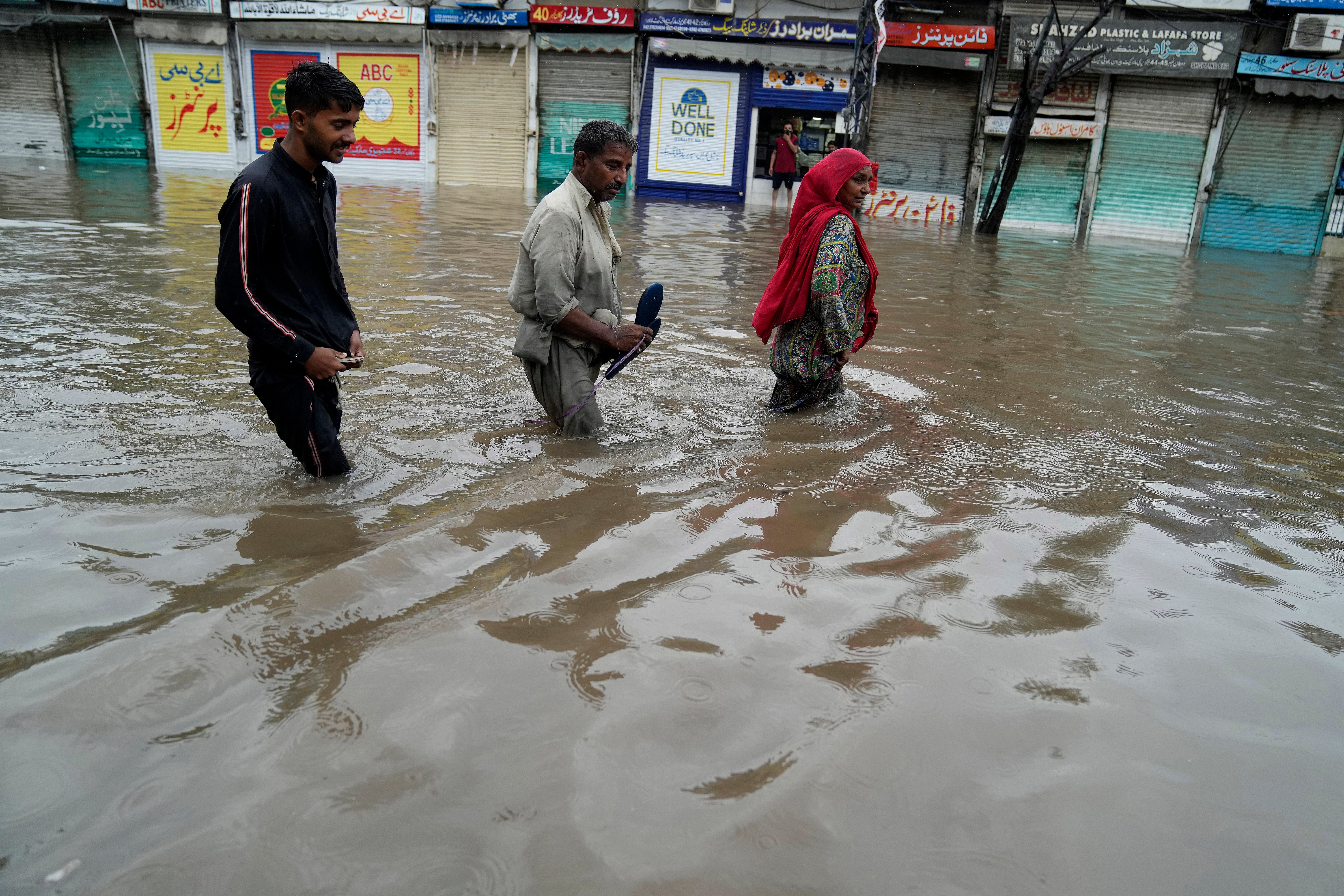 People wade through a flooded area caused by heavy monsoon rainfall in Lahore, Pakistan