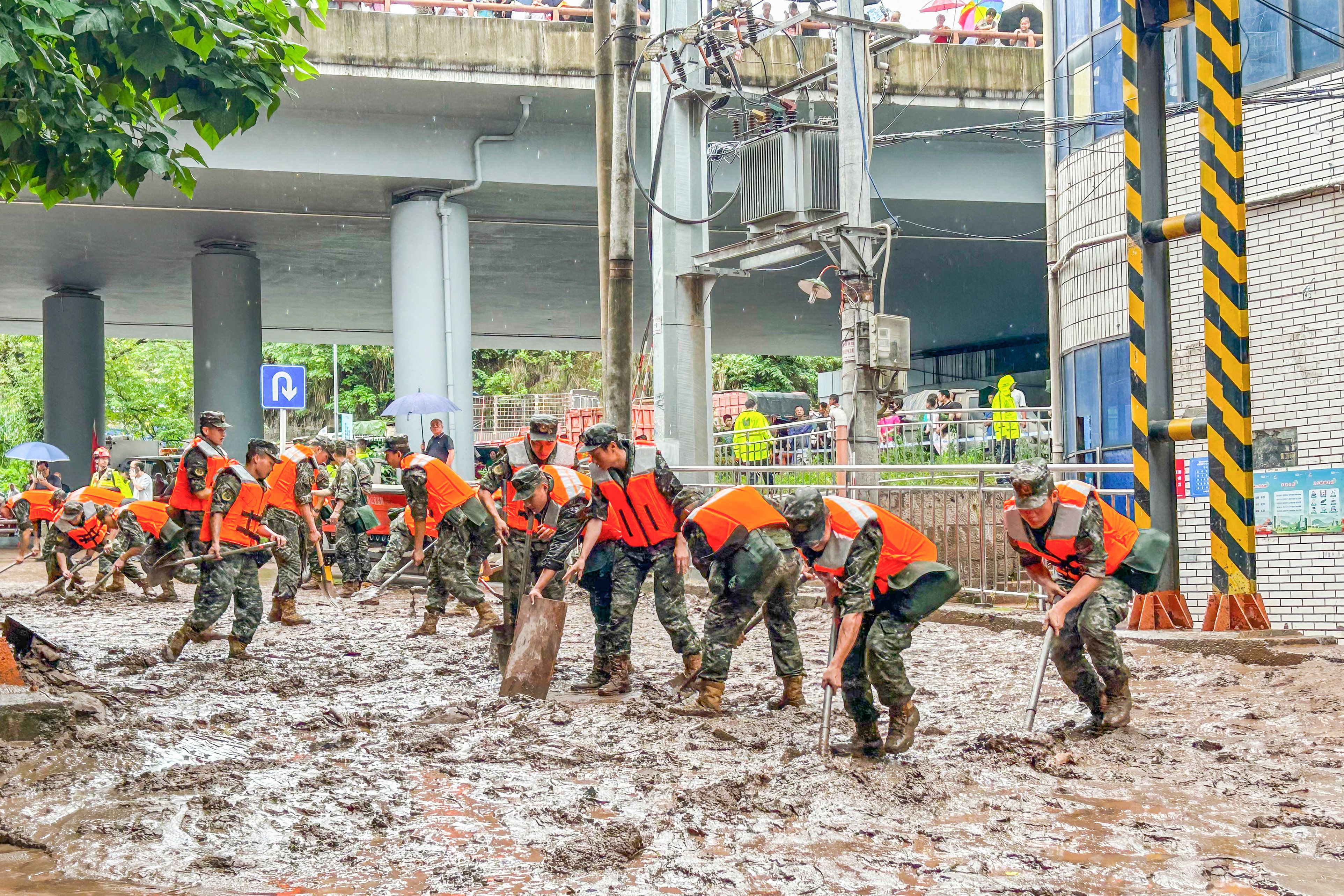 Paramilitary policemen clear a street after flooding caused by heavy rains in China’s southwestern Chongqing