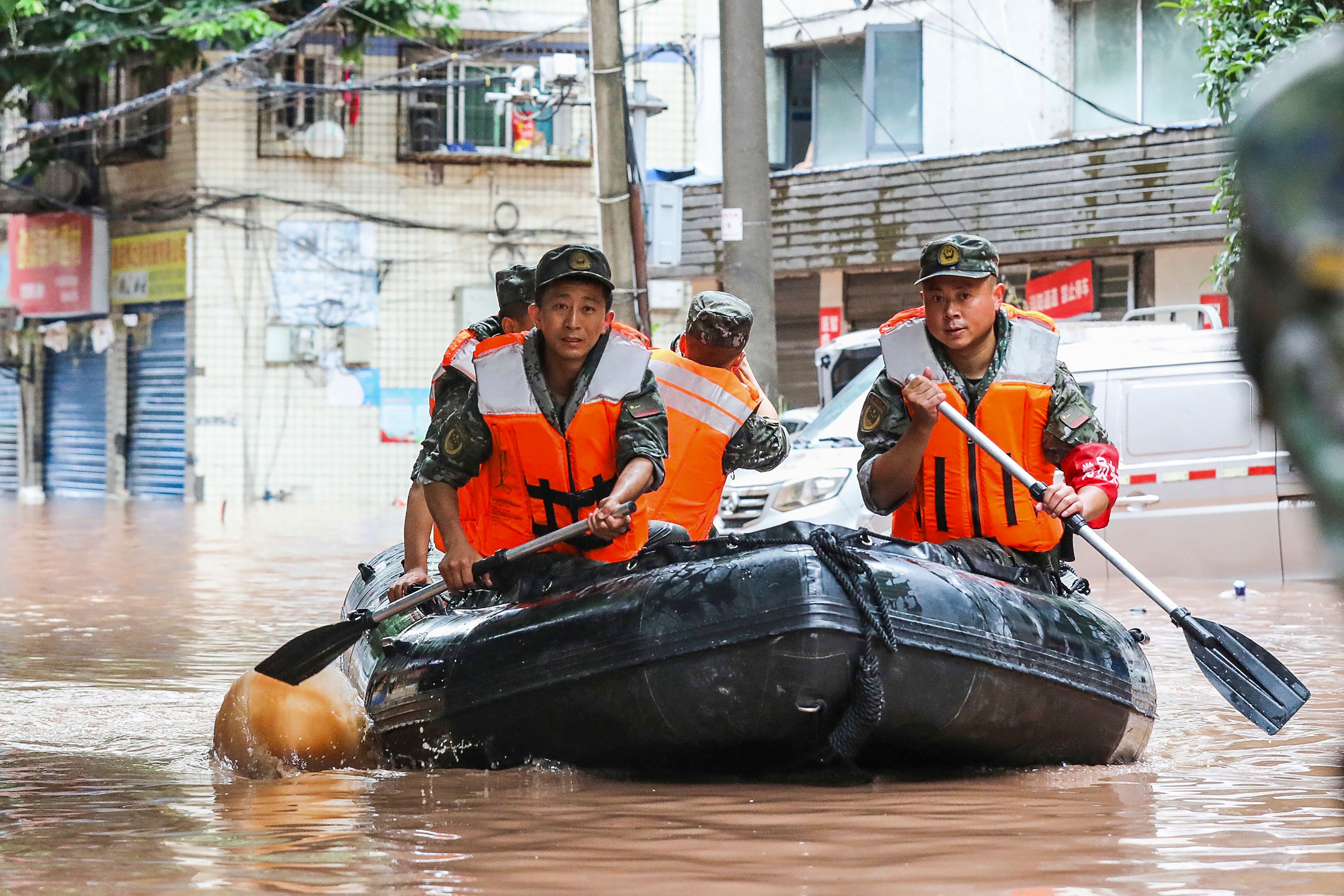 Paramilitary policemen search an area after it was flooded by heavy rains in China’s southwestern Chongqing on 4 July