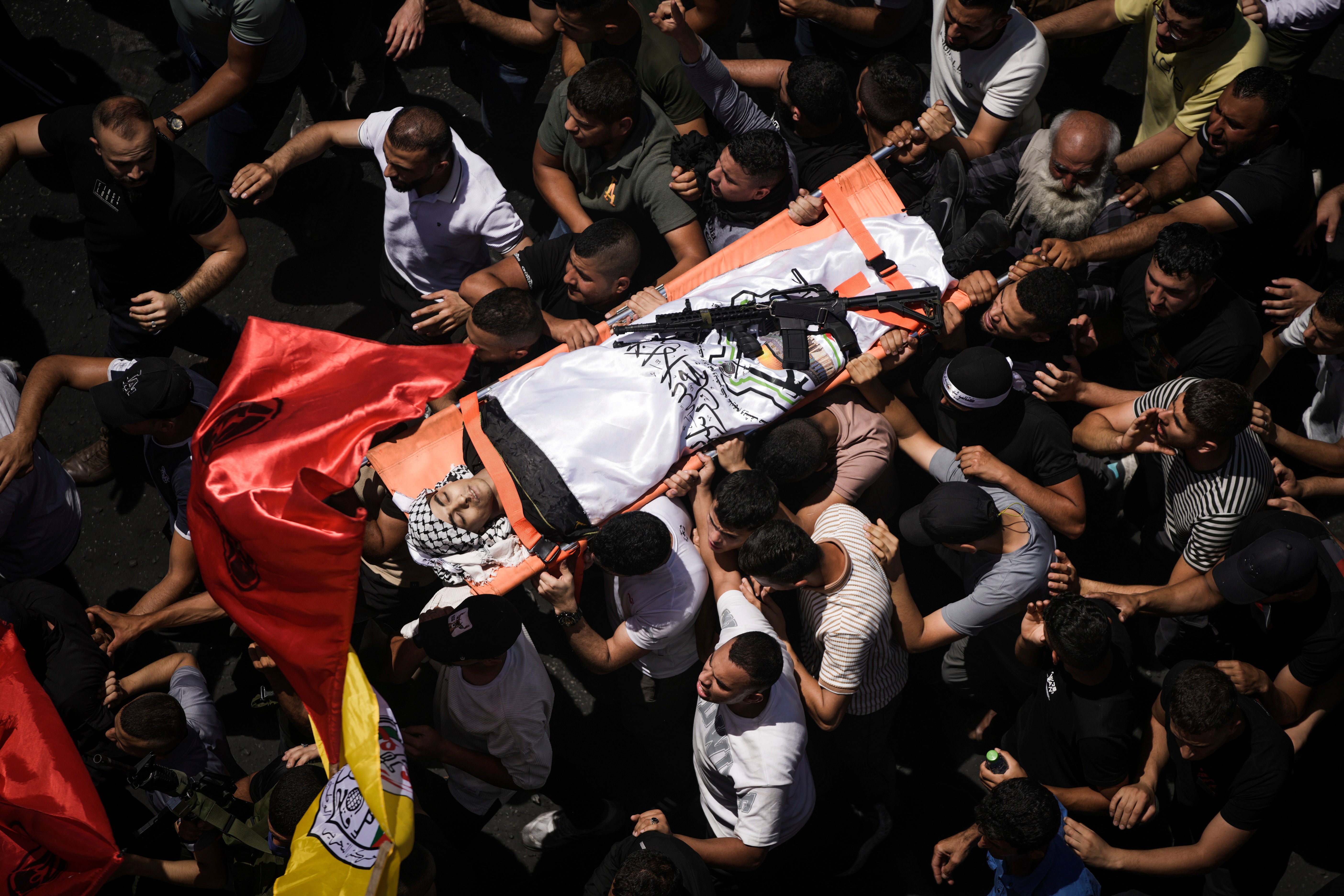 Mourners carry the body of a Palestinian man draped in the flag of the Al Aqsa Martyrs Brigade