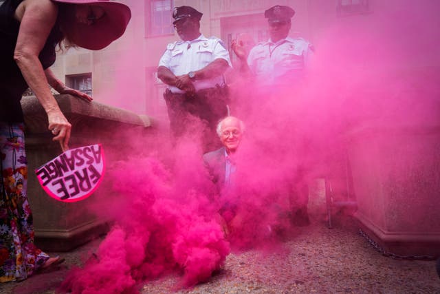 <p>Ben Cohen, co-founder of the Ben & Jerry's ice cream company, sits blocking the entrance to the Department of Justice, as pink smoke is fanned by Jodie Evans, left, co-founder of protest group CODEPINK, before they were detained for blocking the entrance of the Department of Justice in Washington on Thursday, July 6, 2023, after first burning a replica of the Bill of Rights in protest of the Justice Department's prosecution of Wikileaks founder Julian Assange. </p>