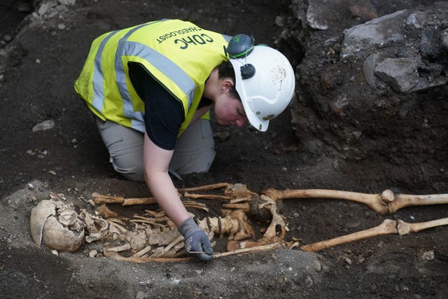 A member of the archaeology team works on a skeleton at an ancient burial site on the new Bullitt Hotel development site (Brian Lawless/PA)