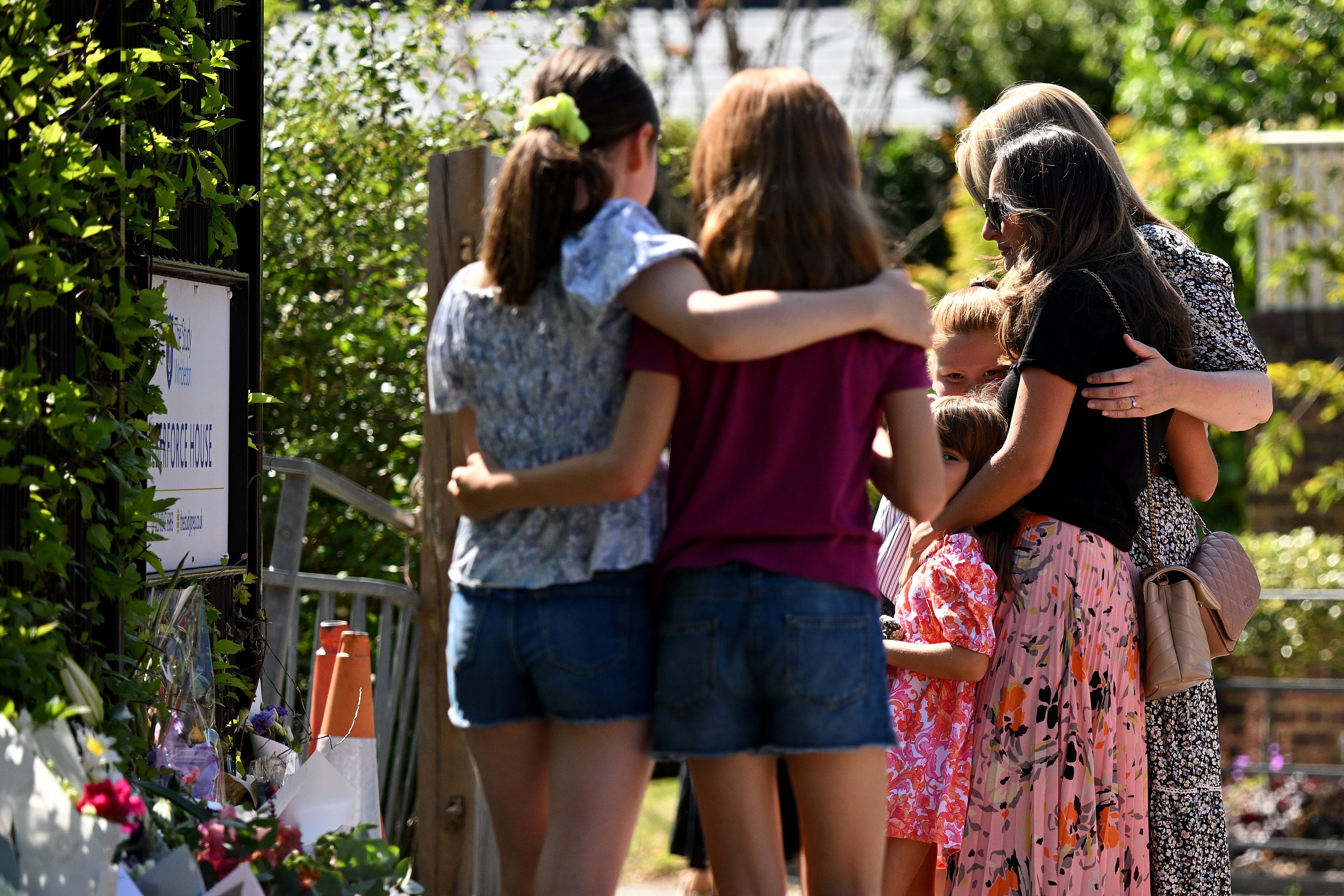 People arrive to lay flowers in tribute to the victims of a car crash outside The Study Preparatory School on Camp Road