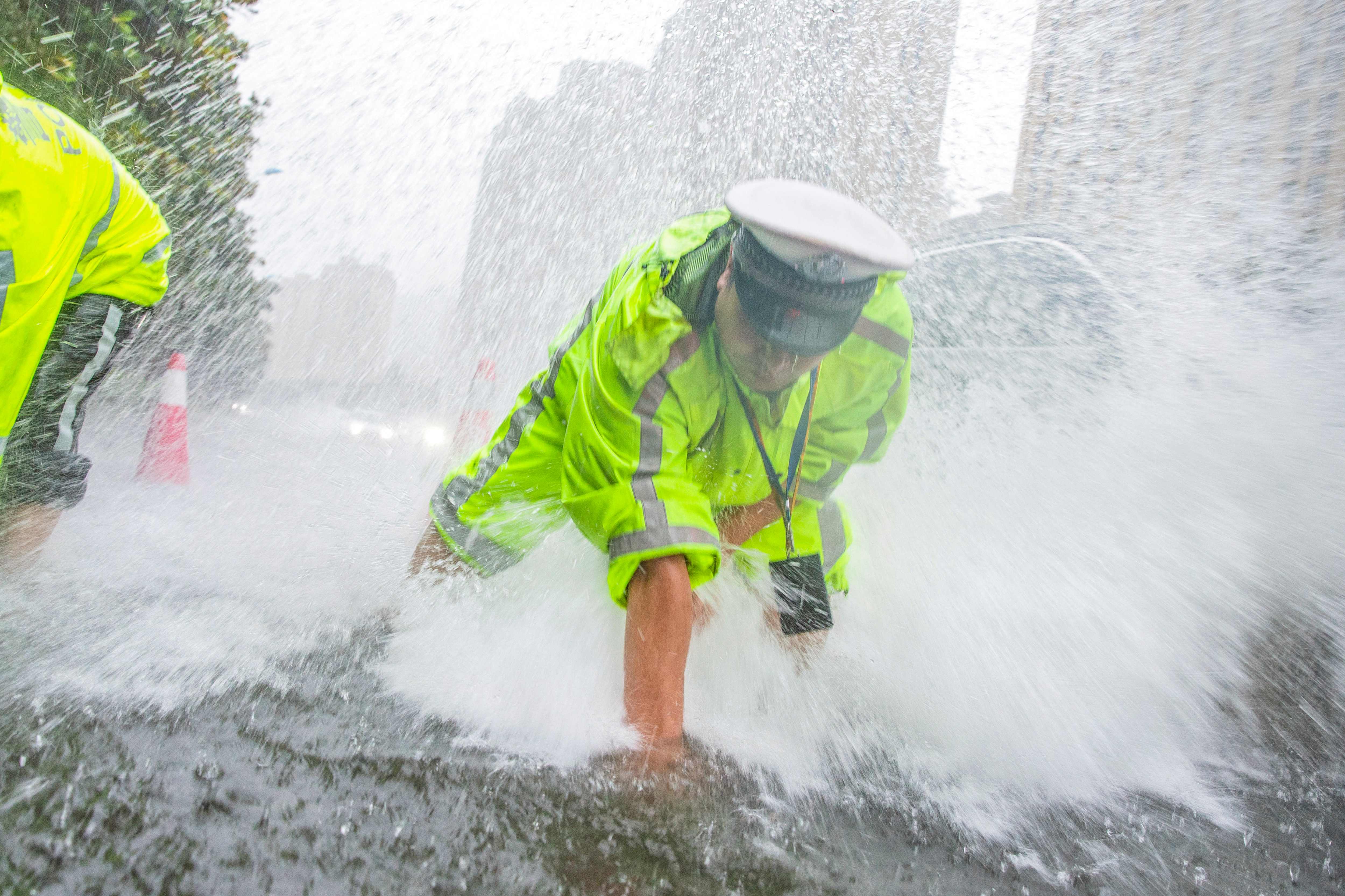 A traffic police officer drains water on a street during a downpour in Nantong, in China’s eastern Jiangsu province