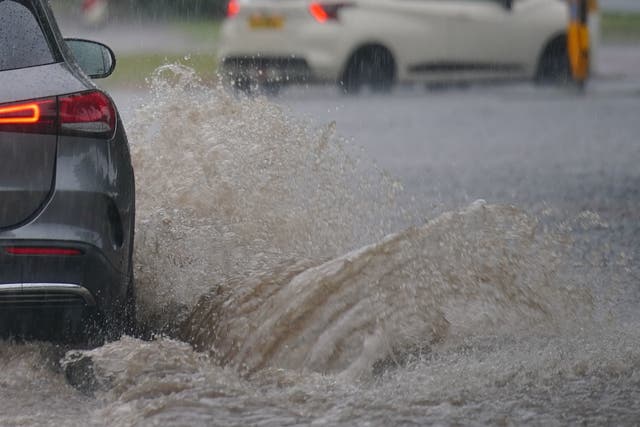 <p>Cars drive through a flooded road after heavy rain in Speke, Liverpool</p>