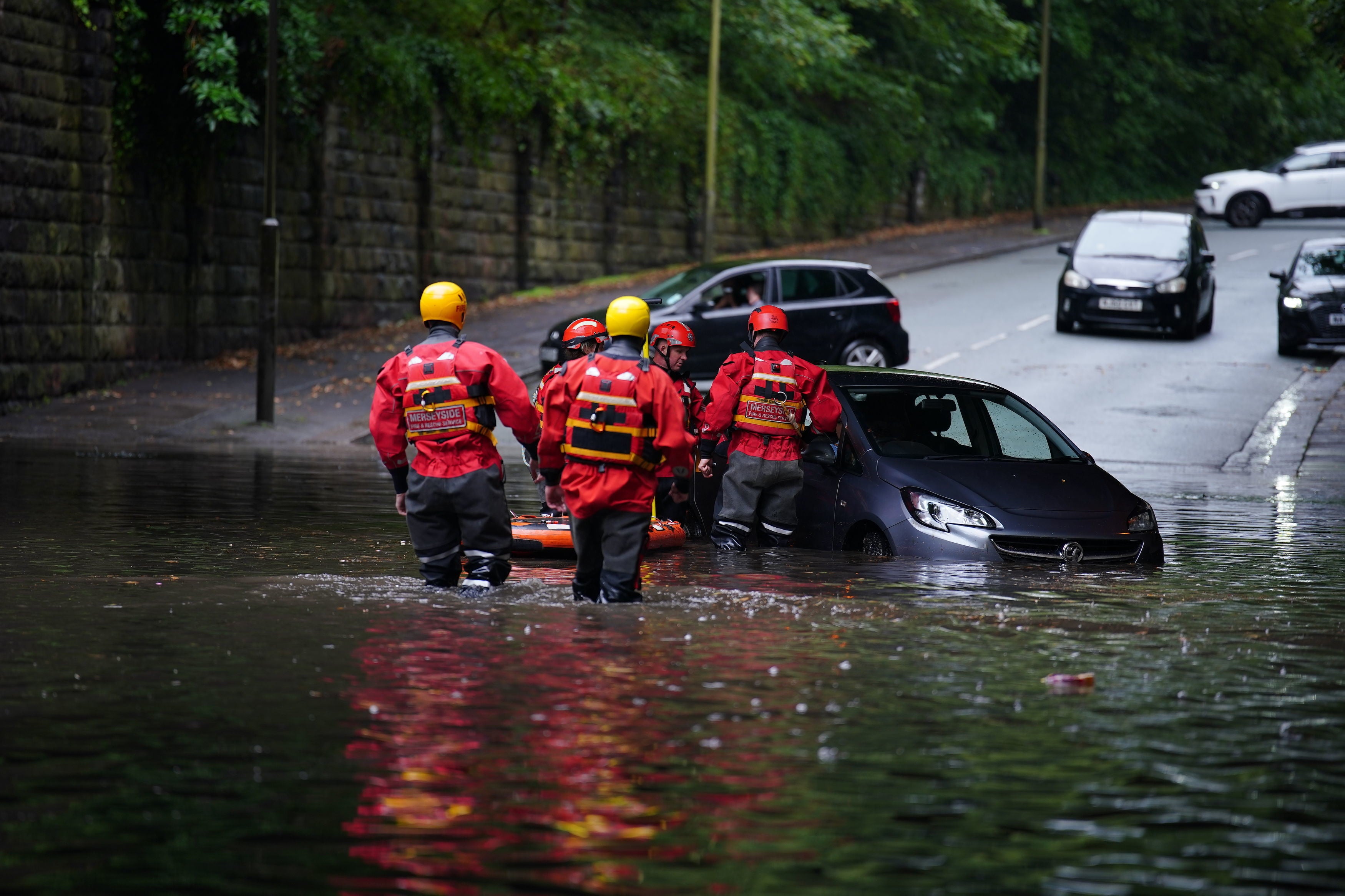 Emergency services rescue a woman from her vehicle after it got stranded on a flooded road in Mossley Hill, Liverpool