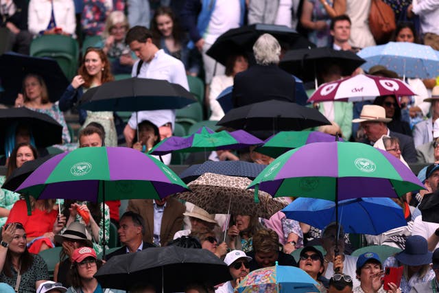 Spectators shelter from the rain at Wimbledon (Steven PAston/PA)
