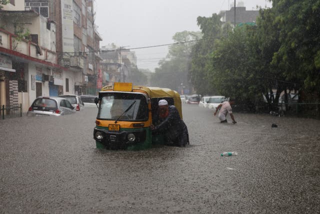 <p>A man pushes his rickshaw in a flooded street after heavy rains in New Delhi, India on 8 July</p>
