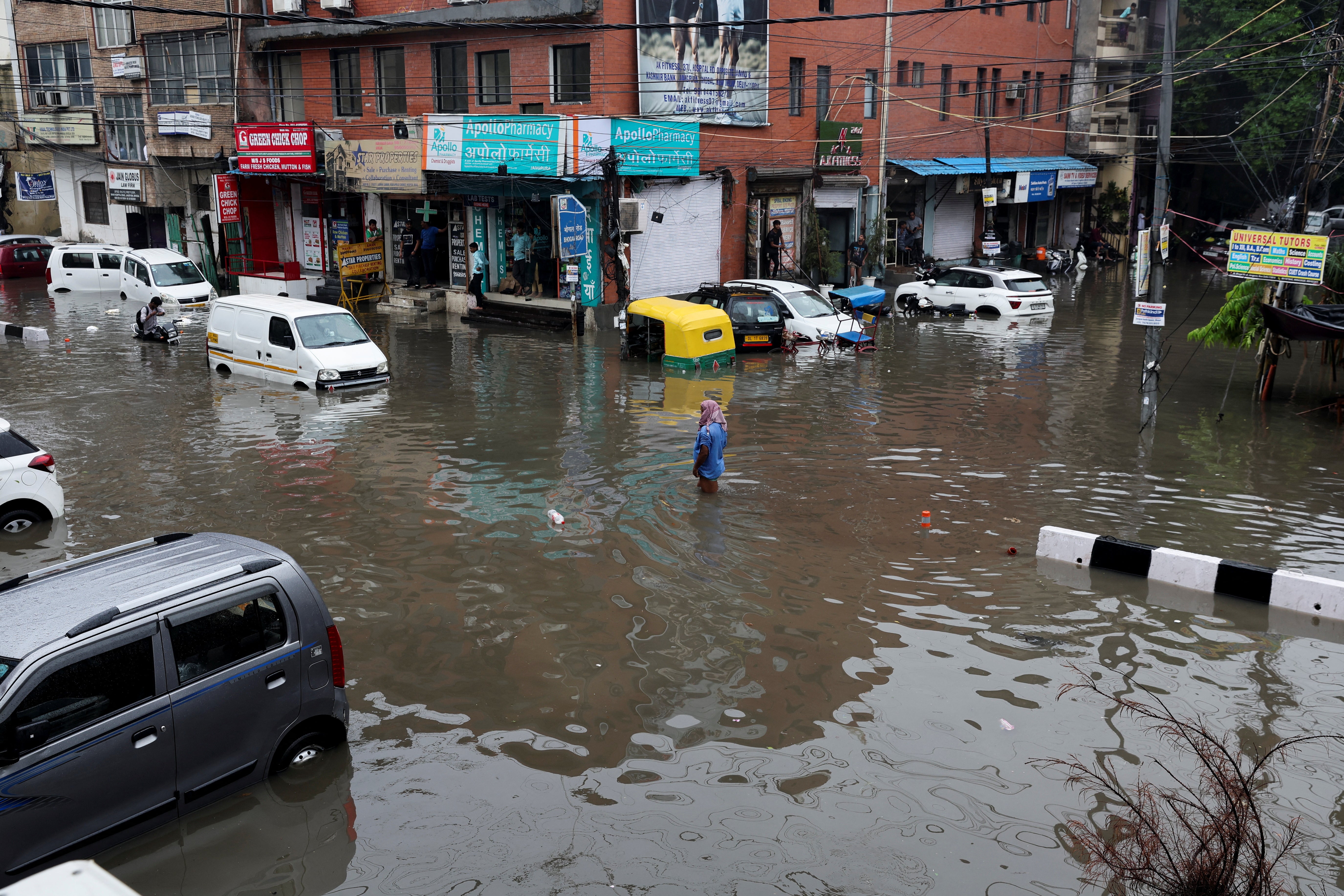 A person wades through a flooded street after heavy rains in New Delhi
