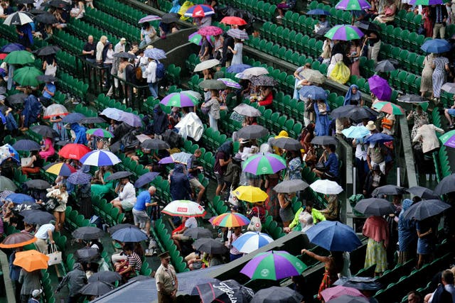 Spectators sheltering from the rain at Wimbledon on Saturday (Zac Goodwin/PA)