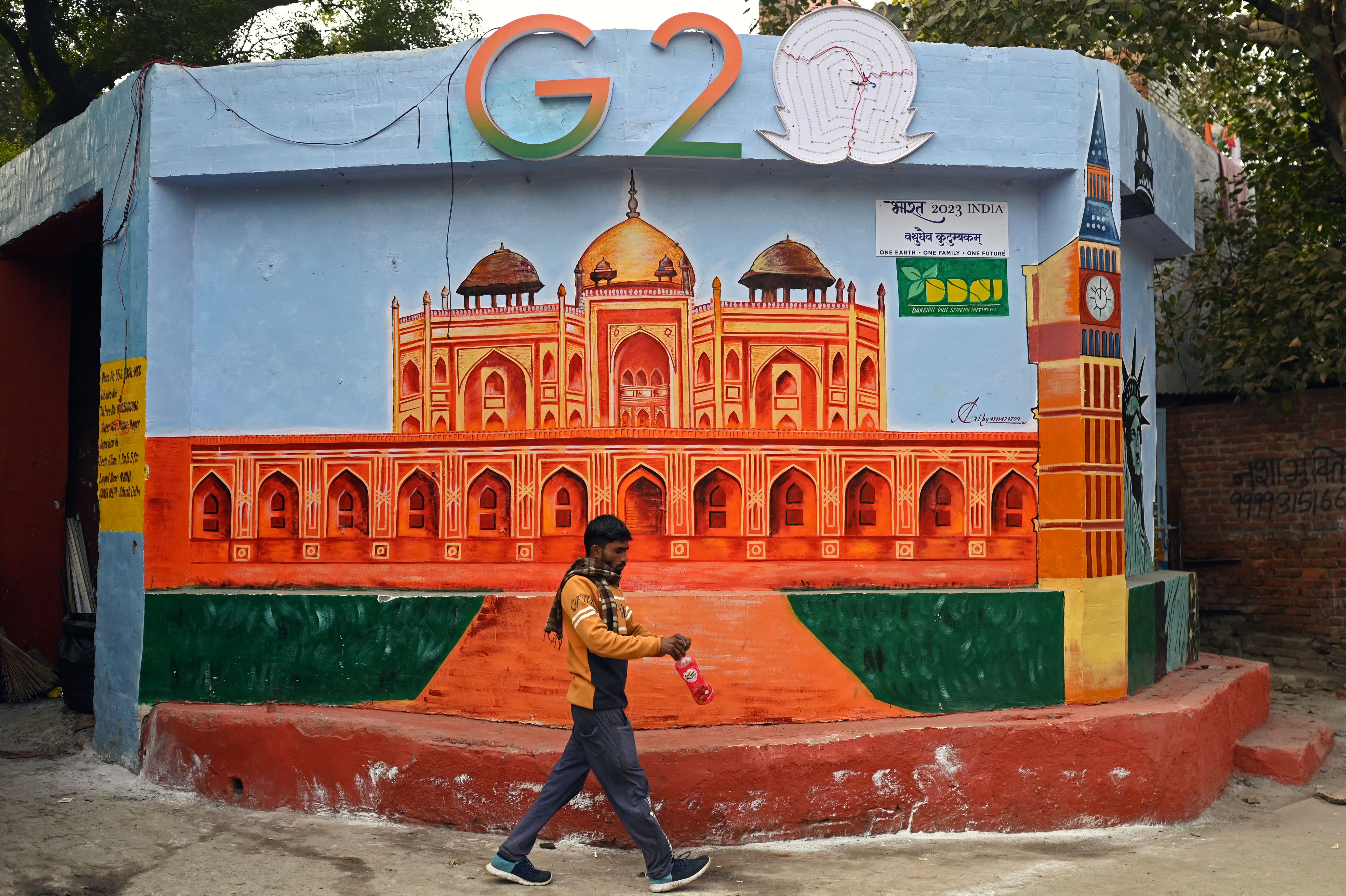 A man walks past a wall mural of Humayun’s tomb under the logo of G-20 Summit, in New Delhi