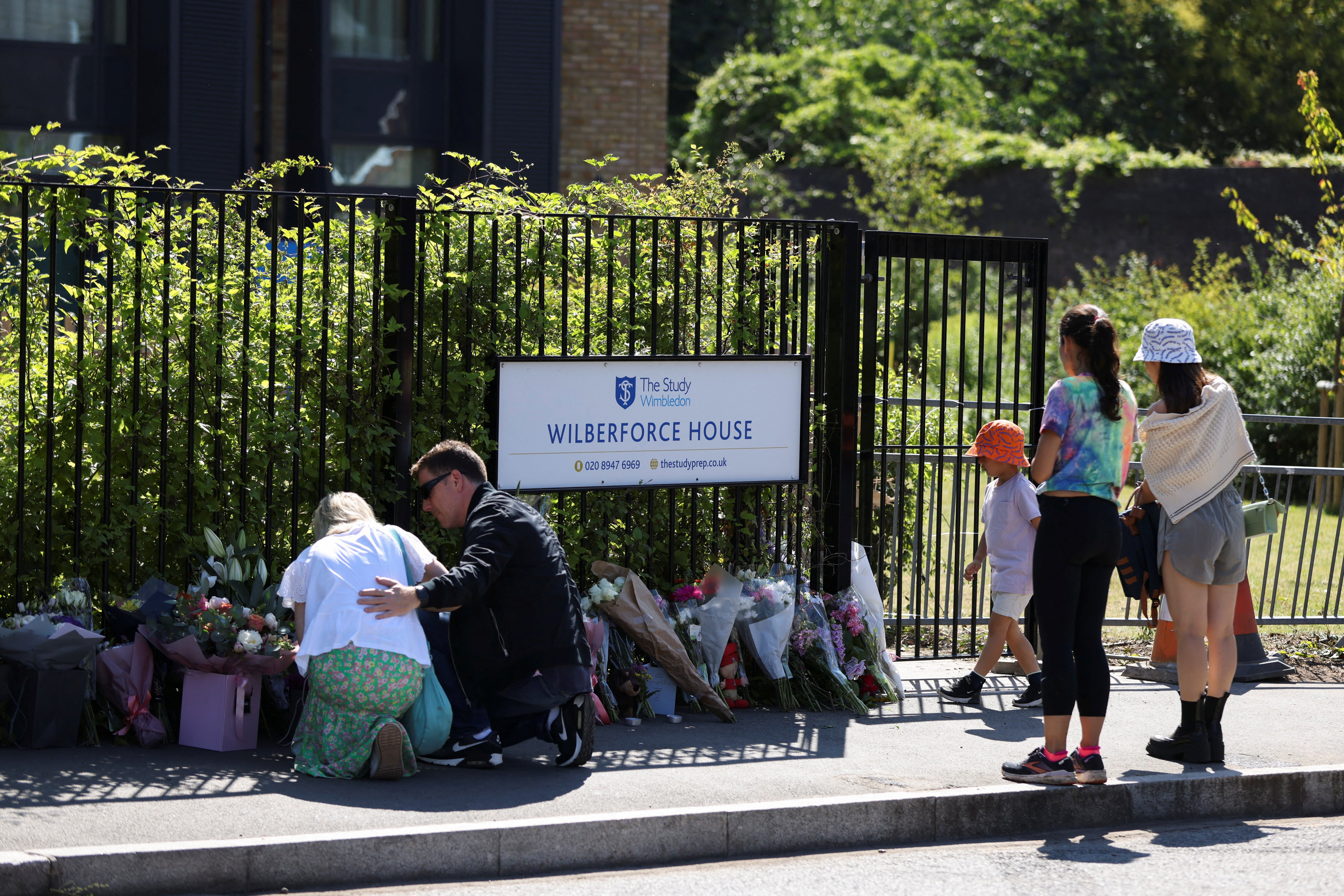 People lay flowers in tribute to the victims of the crash outside the Study Prep school in Wimbledon