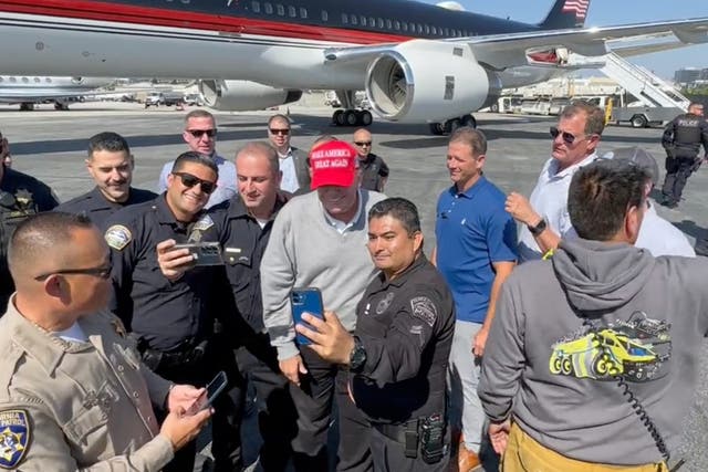 <p>Mr Trump poses for photos with law enforcement officers in Los Angeles</p>