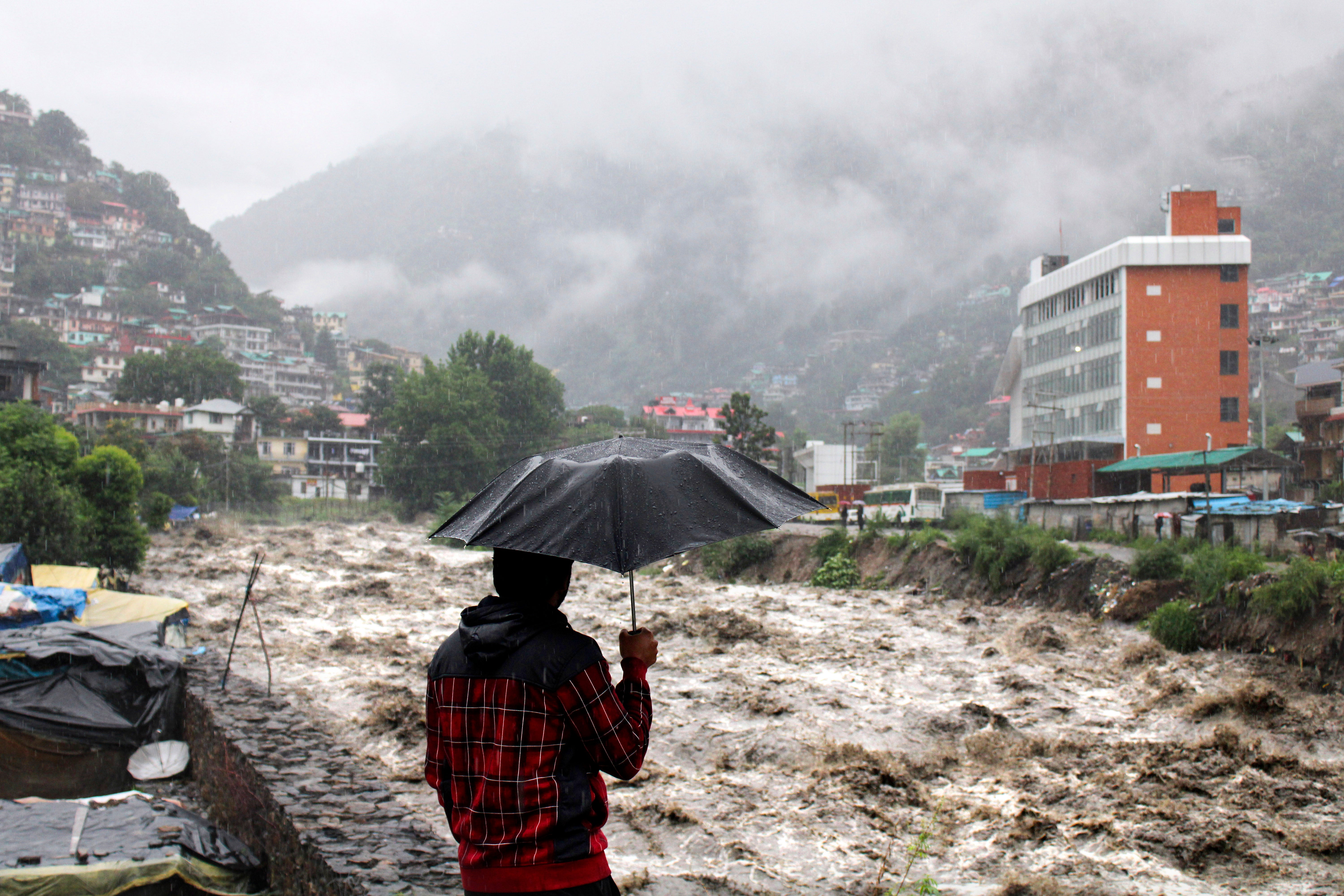 A man looks at the swollen Beas River following heavy rains in Kullu, Himachal Pradesh, India