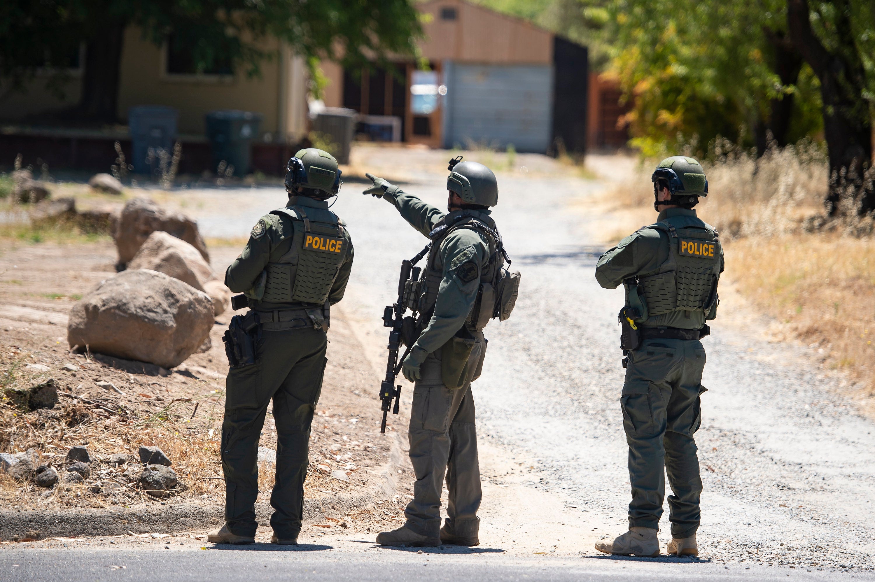 A Placer County Sheriff's deputy, joined by two police officers, points toward a home on Greenbrae Road