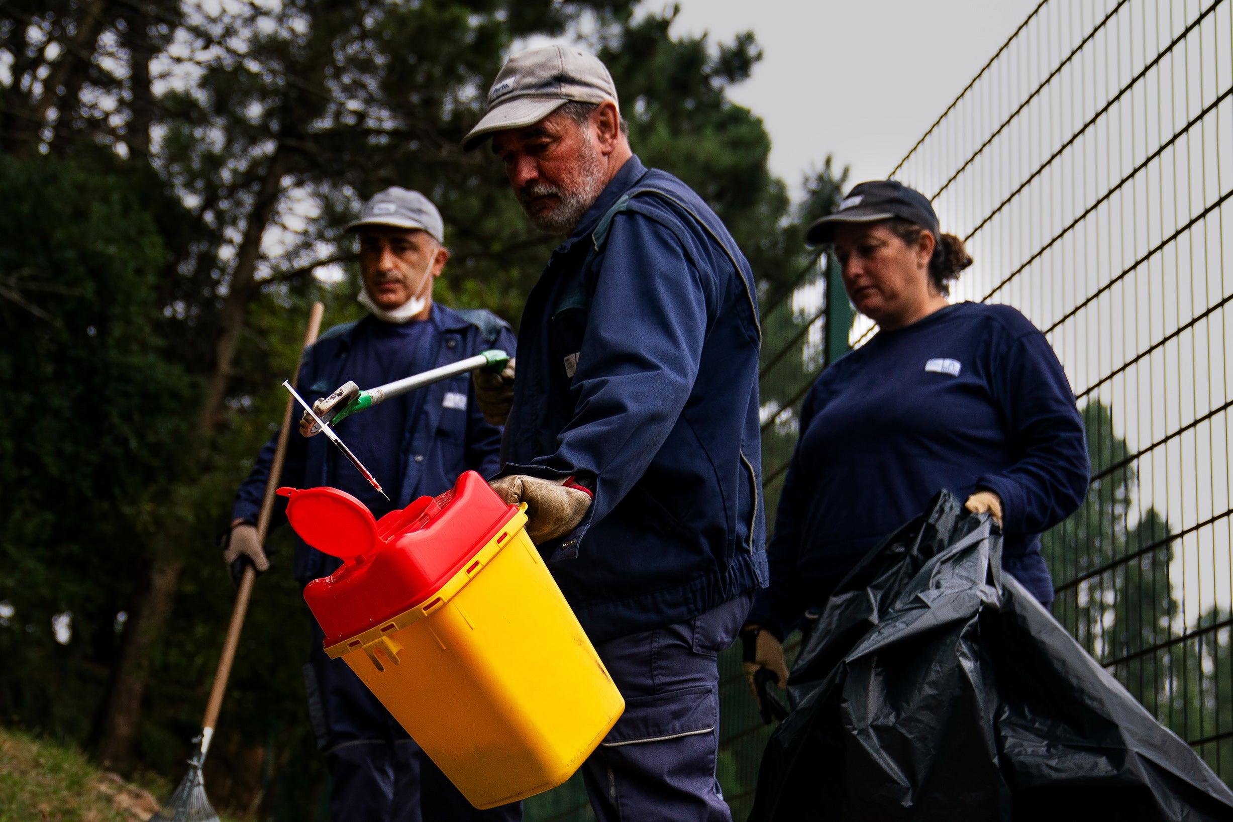 Municipal workers dispose of a used syringe at the Mata da Pasteleira park in Porto